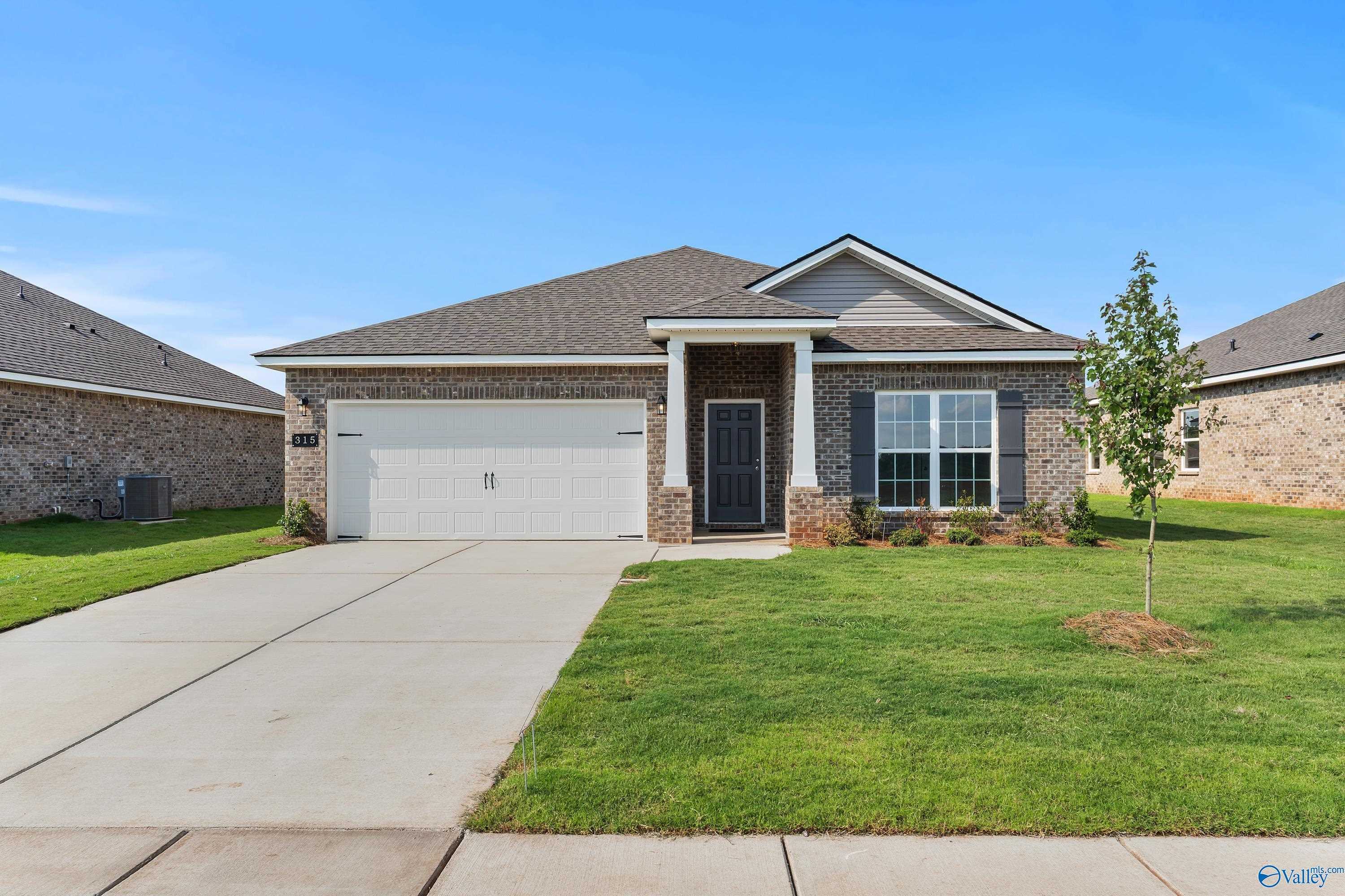 Modern gray brick 1-story home with 2-car garage, driveway, and lush lawn in Clearview, Hazel Green, Alabama - Davidson Homes The Daphne