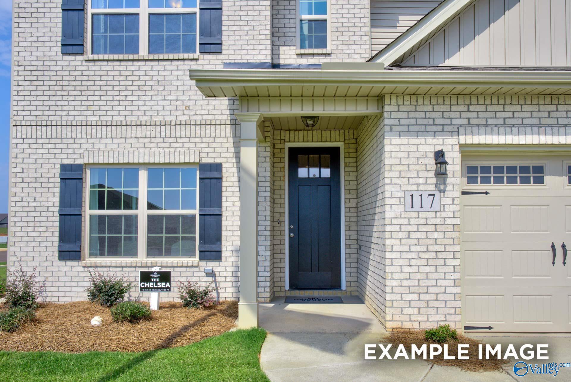 White brick exterior with covered front porch and navy shutters on The Chelsea A by Davidson Homes in Ivy Hills, Toney, Alabama