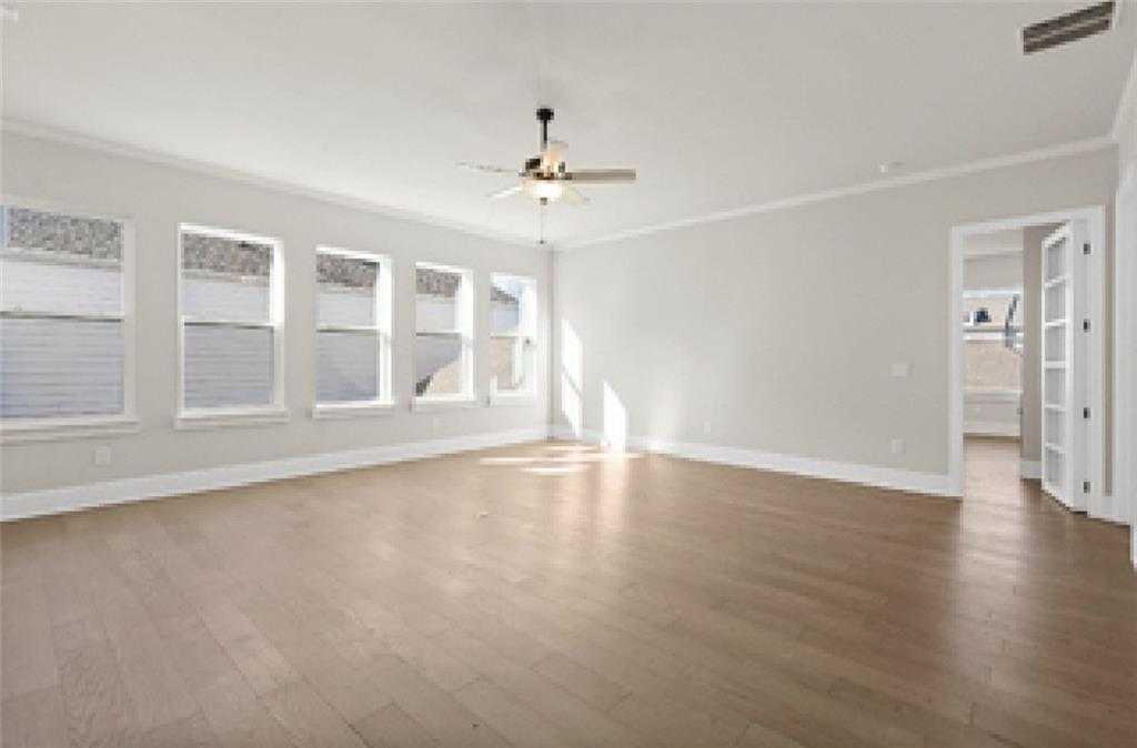 Spacious living room with light hardwood floors, large shuttered windows, ceiling fan in Davidson Homes Seaside A, Woodstock, GA