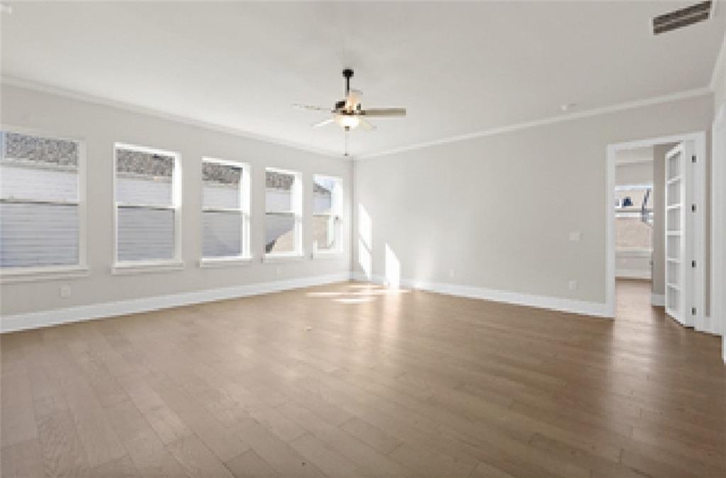 Spacious living room with light hardwood floors, large shuttered windows, ceiling fan in Davidson Homes Seaside A, Woodstock, GA