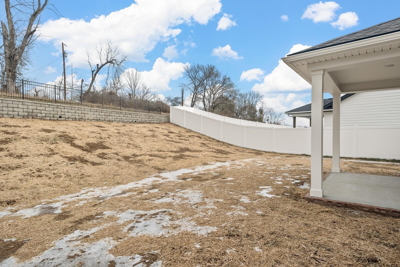 Private fenced backyard with covered patio and sloped hill in 3-bedroom The Logan C home, Woods Crossing, Gallatin, Tennessee