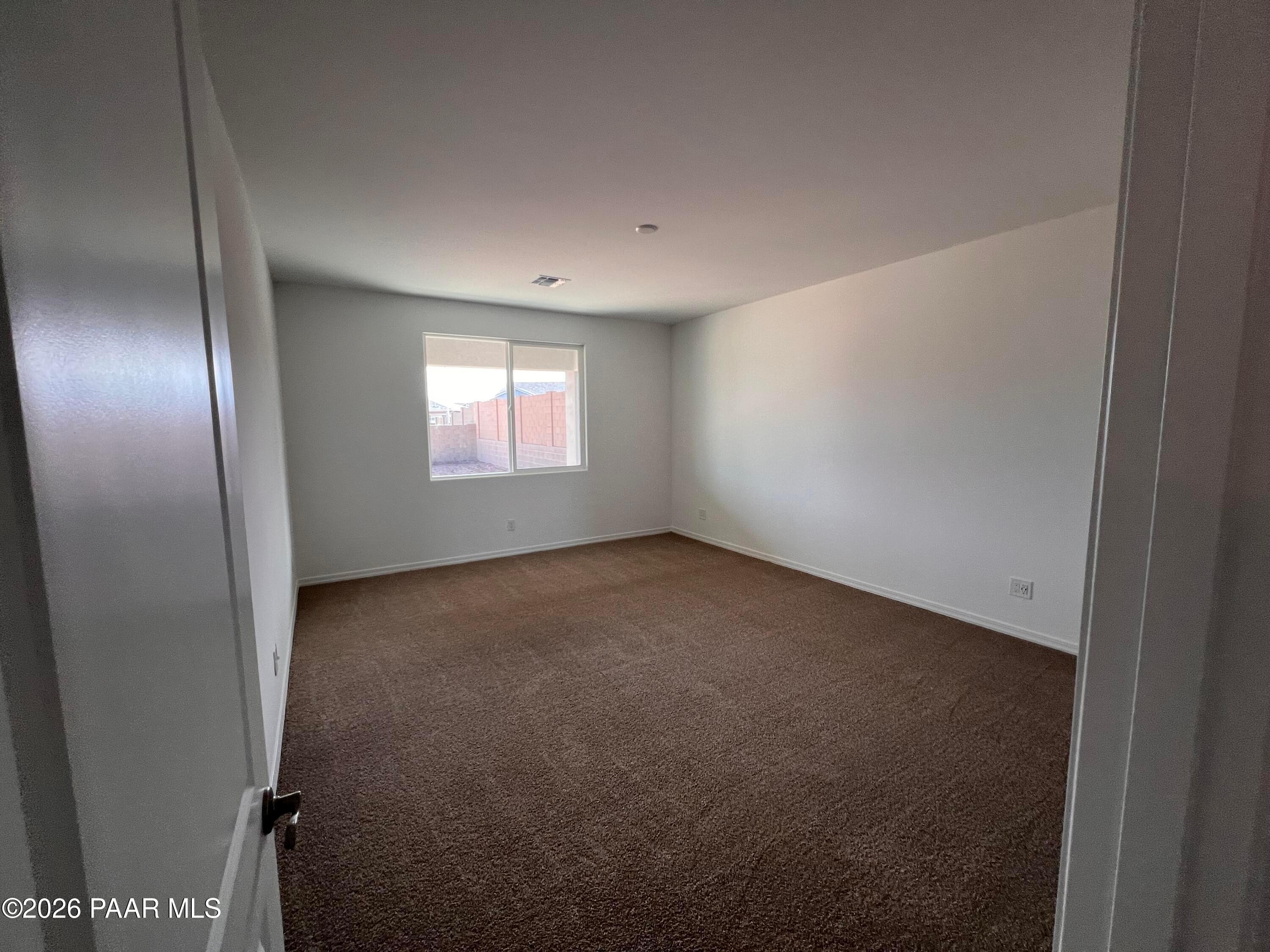 Spacious empty bedroom with beige carpet, white walls, and large window in Davidson Homes The Monarch A, Prescott, Arizona