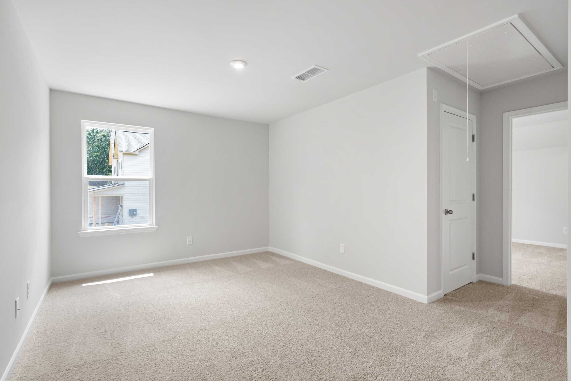 Spacious secondary bedroom in The Ash B at Wehunt Meadows, Hoschton GA, featuring gray walls, large window, and beige carpet