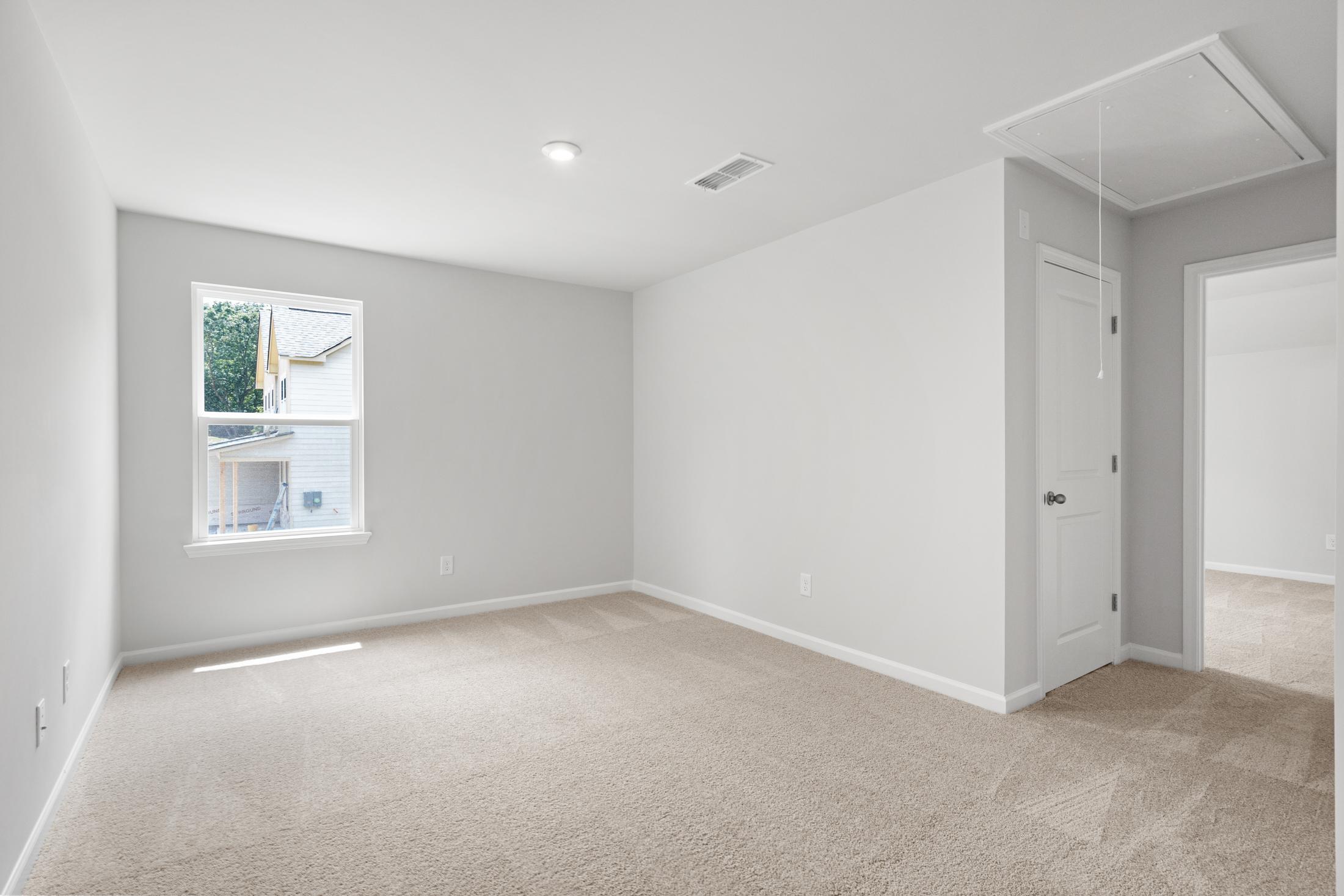 Spacious secondary bedroom in The Ash B at Wehunt Meadows, Hoschton GA, featuring gray walls, large window, and beige carpet