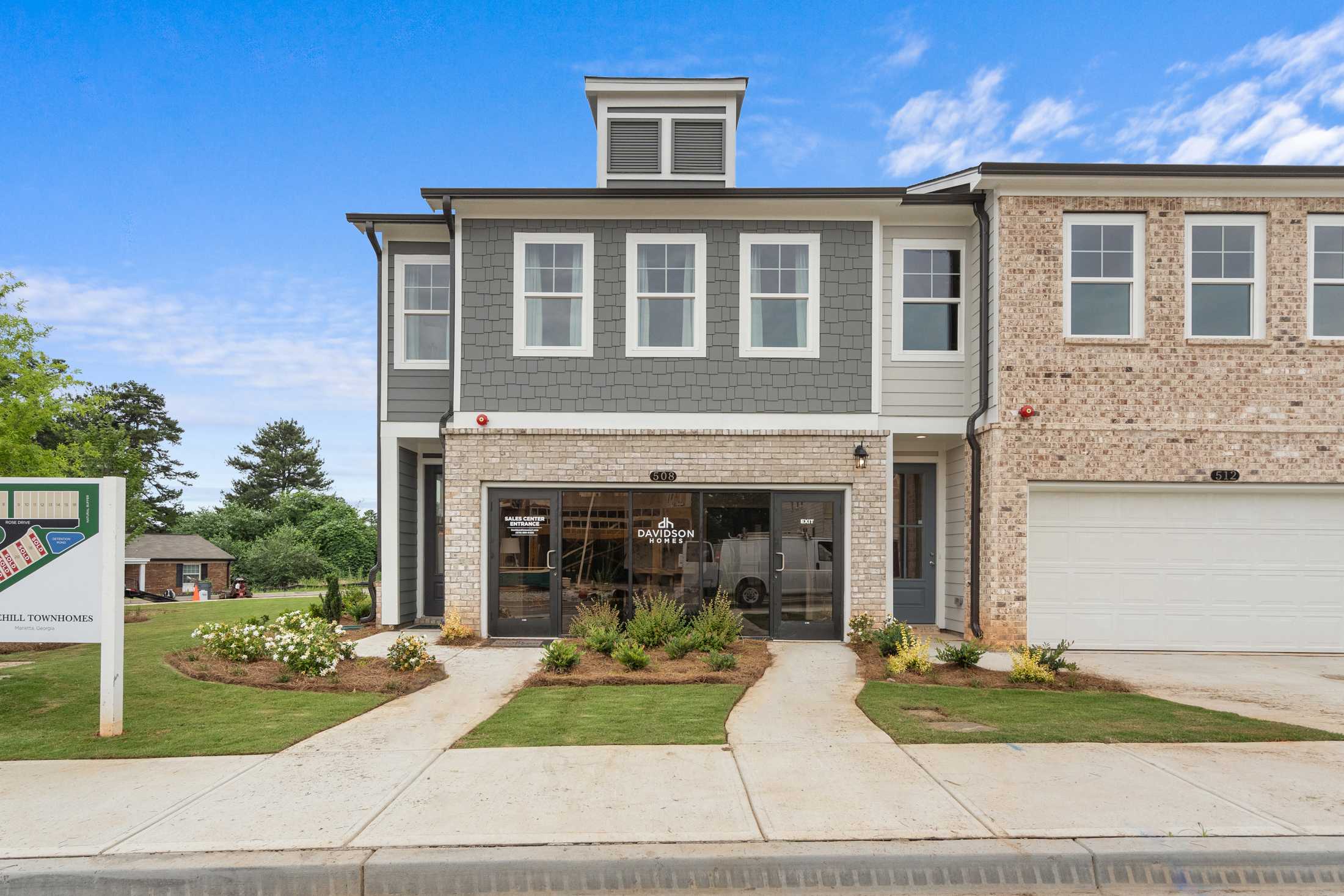 Modern townhome exterior at Rosehill Townhomes in Marietta GA with gray siding, brick accents, glass garage door and landscaped entry