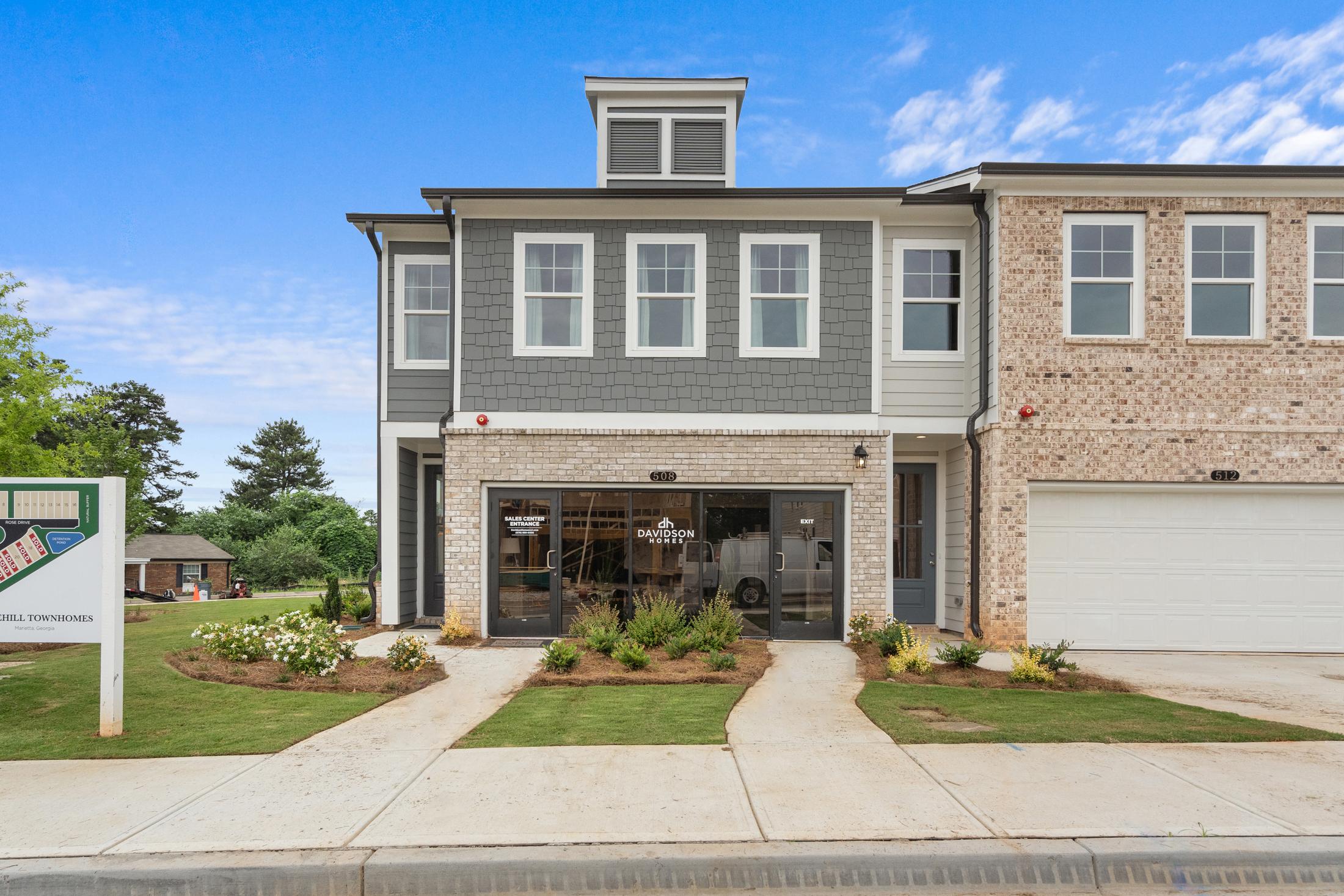 Modern townhome exterior at Rosehill Townhomes in Marietta GA with gray siding, brick accents, glass garage door and landscaped entry