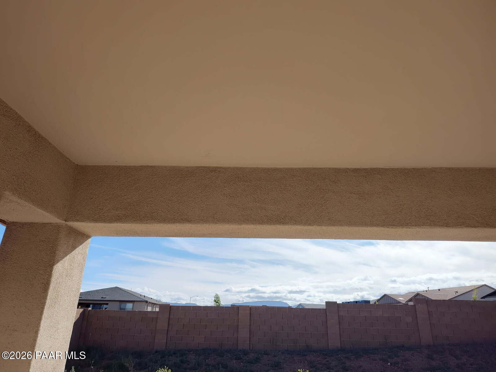 Covered patio archway with stucco ceiling overlooking backyard fence, desert mountains, and homes in North Ridge Pronghorn Ranch, Prescott Valley, AZ