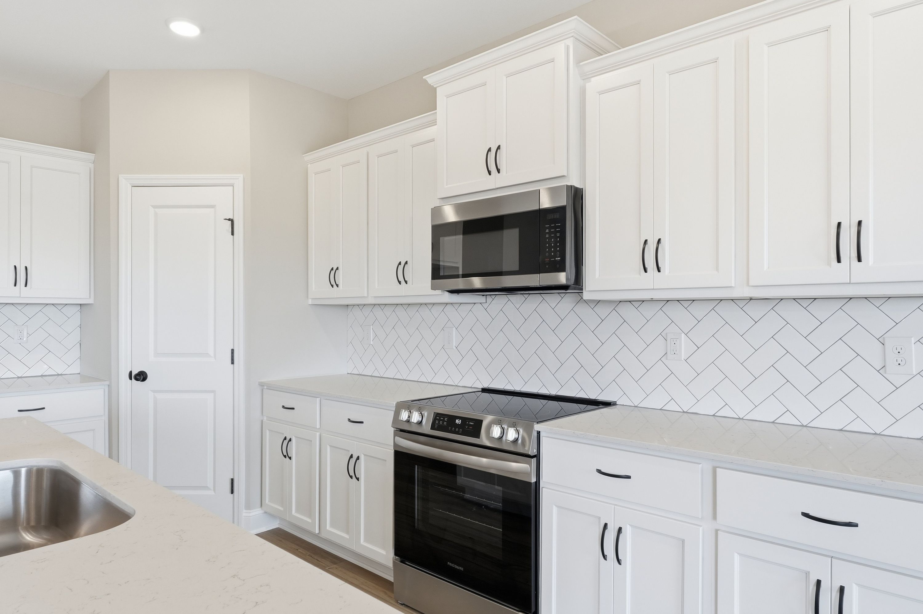 Spacious Rockford kitchen by Davidson Homes featuring white shaker cabinets, stainless steel appliances, and herringbone subway tile backsplash