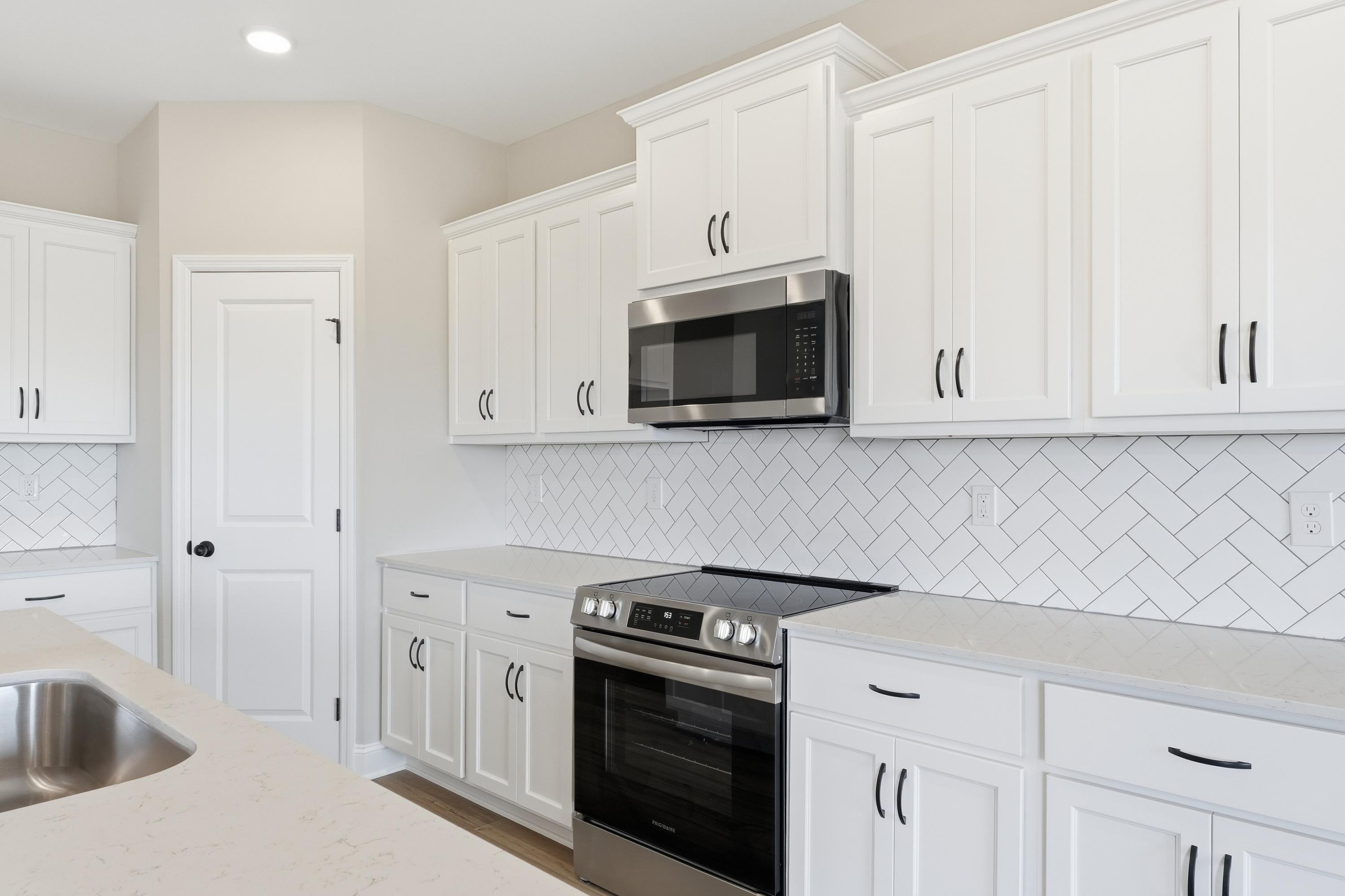 Spacious Rockford kitchen by Davidson Homes featuring white shaker cabinets, stainless steel appliances, and herringbone subway tile backsplash
