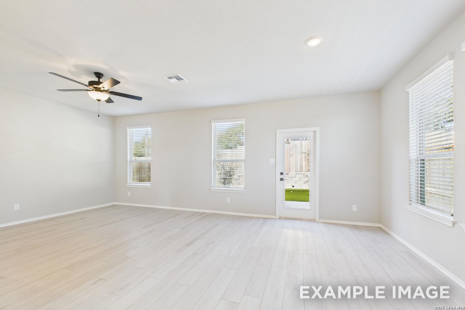Bright, open living room with light wood floors in The Charlotte B floor plan at Cedar Heights, San Antonio.