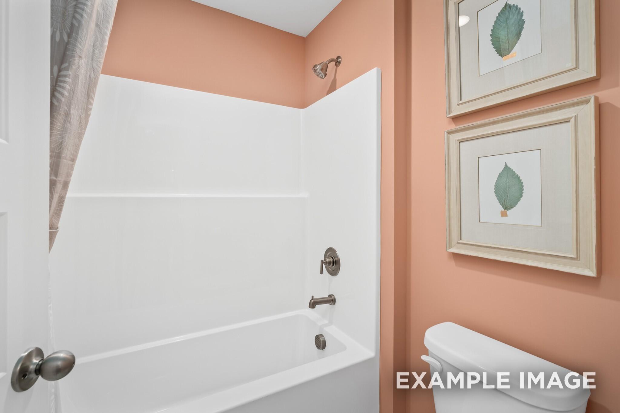 Full bathroom with tub-shower combo and peach walls in The Ash A floor plan at Woods Crossing in Gallatin, Tennessee.