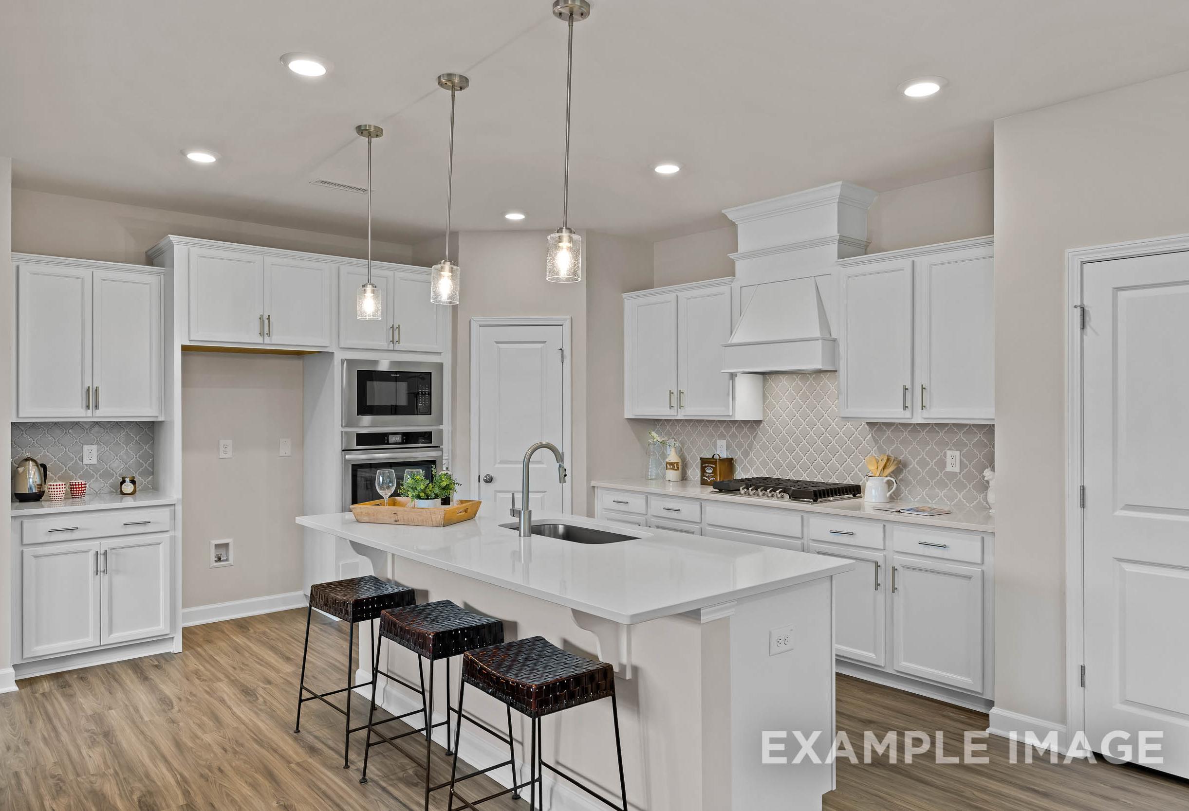 Spacious white kitchen in The Preston A by Davidson Homes with large island, pendant lights, bar stools, and stainless appliances