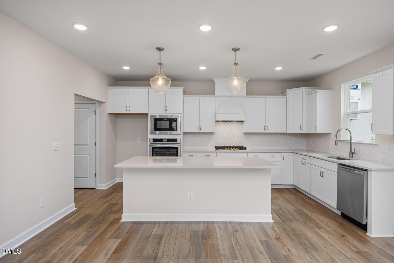 Modern kitchen with white cabinets, quartz countertops, and stainless appliances in The Hickory II C at Montrose, Aberdeen.