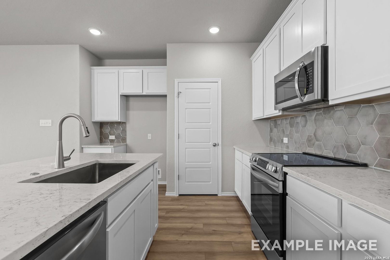 Modern kitchen featuring white shaker cabinets, quartz island, hex tile backsplash, stainless appliances in Davidson Homes The Colorado D, San Antonio
