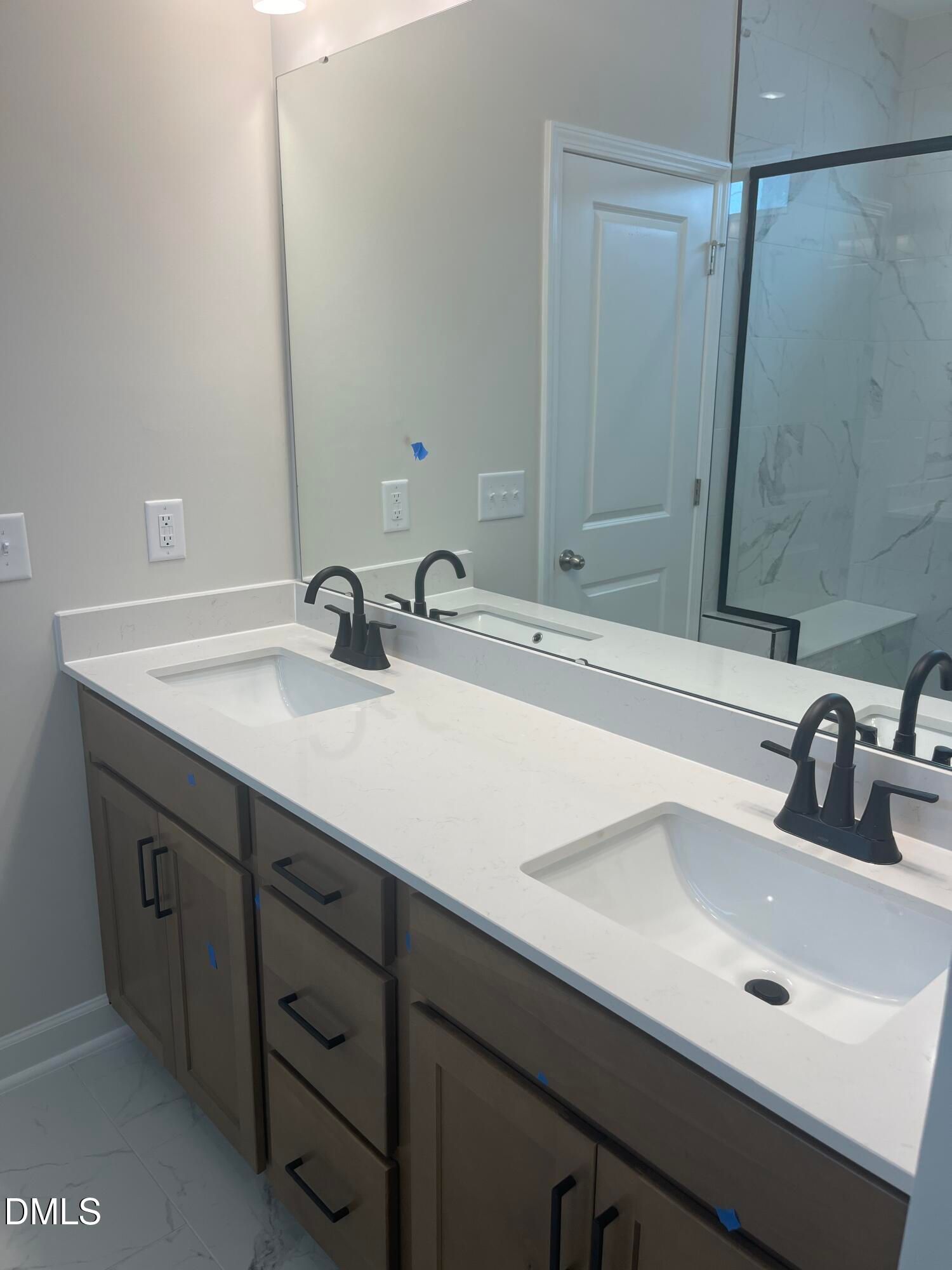 Modern primary bathroom double vanity with quartz counters, black faucets, and glass shower in Davidson Homes Ashport L, Wake Forest NC