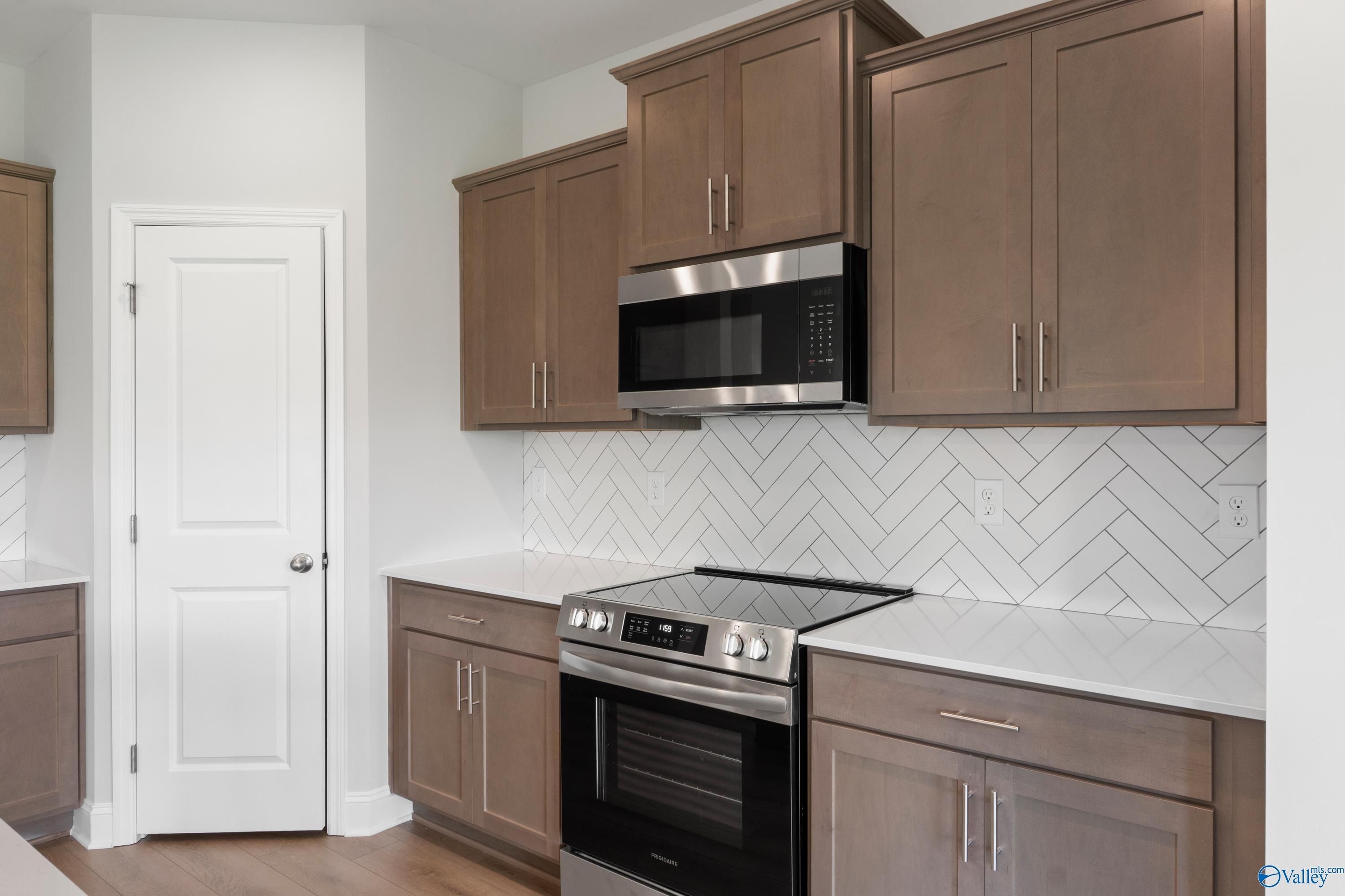 Modern kitchen featuring herringbone subway tile backsplash, shaker cabinets, stainless steel appliances in Davidson Homes The Franklin C, Harvest, AL