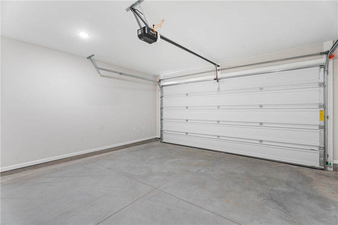 Spacious empty two-car garage with open white door and overhead opener in Davidson Homes The Luna B, Opelika, Alabama