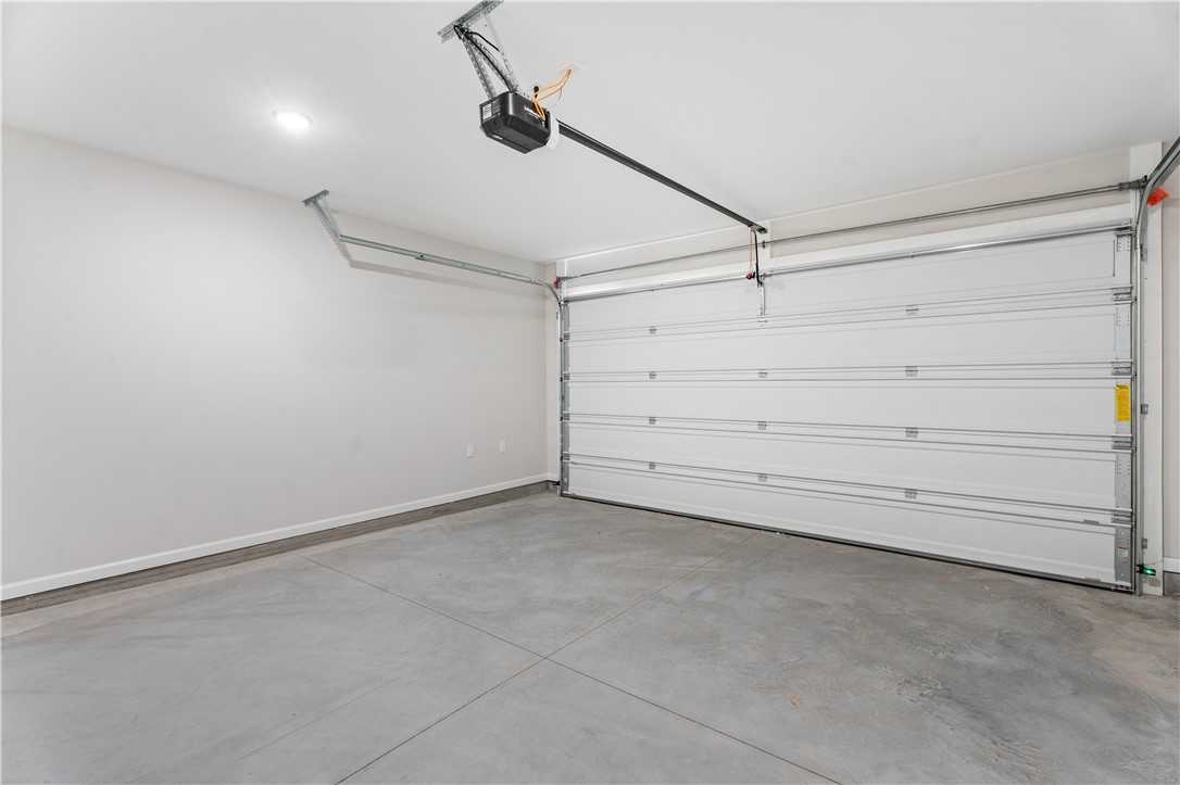 Spacious empty two-car garage with open white door and overhead opener in Davidson Homes The Luna B, Opelika, Alabama
