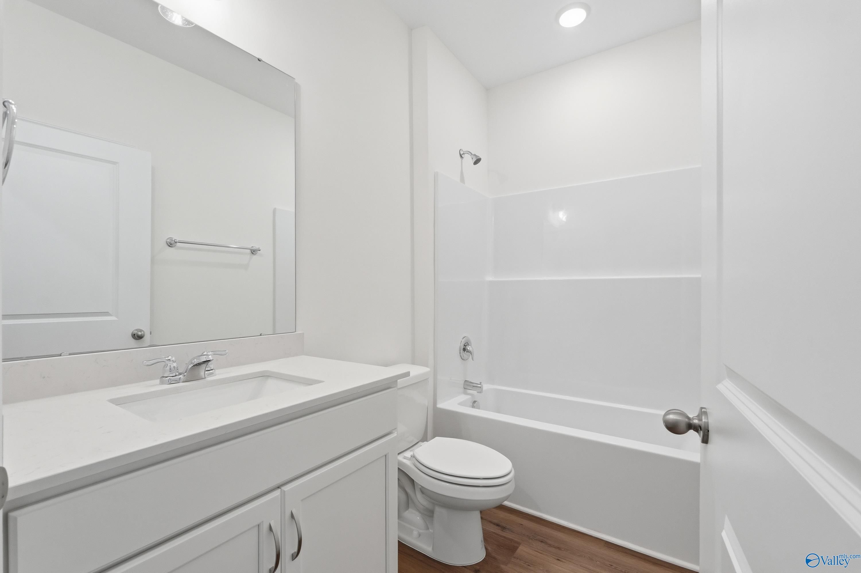 Modern white bathroom featuring bathtub-shower combo, single vanity sink, and toilet in Davidson Homes The Cumberland D, Decatur, Alabama