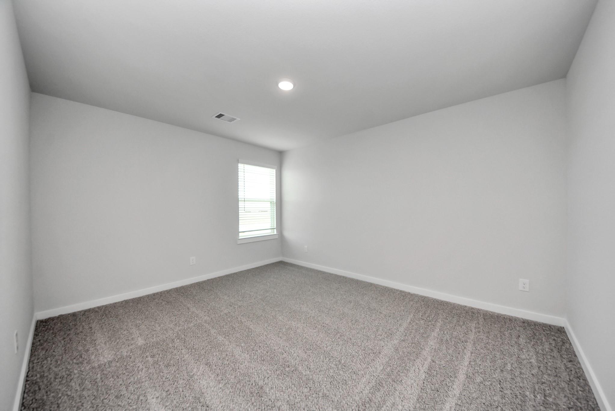Spacious empty bedroom with carpet and window in Davidson Homes The San Marcos E floor plan at Emberly, Beasley, Texas