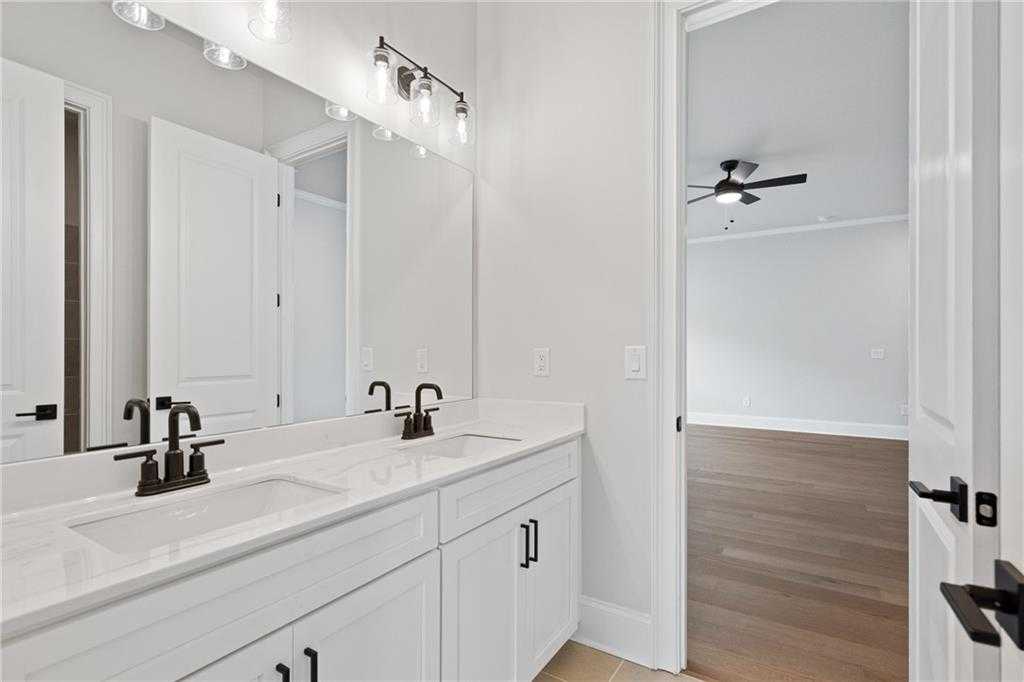 Modern master bathroom double vanity with white quartz counters, black faucets, and large mirror in Davidson Homes The Seaside B, Woodstock, GA