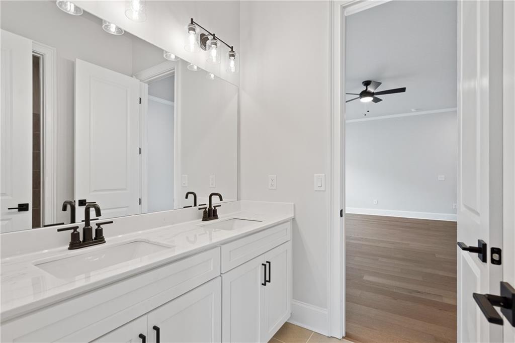 Modern master bathroom double vanity with white quartz counters, black faucets, and large mirror in Davidson Homes The Seaside B, Woodstock, GA