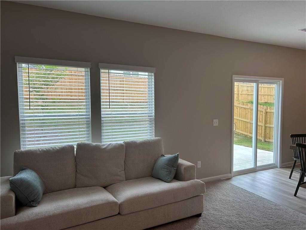 Cozy living room with beige sofa, large windows with blinds, and sliding door to fenced backyard in Davidson Homes The Bartlett, Phenix City, Alabama