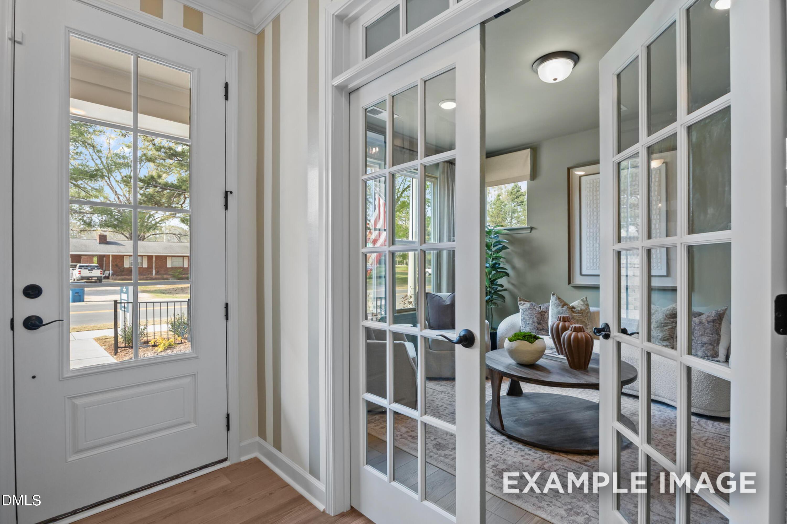 French doors opening to cozy sitting room with striped accent wall and glass entry door in Davidson Homes' The Avery, Knightdale NC