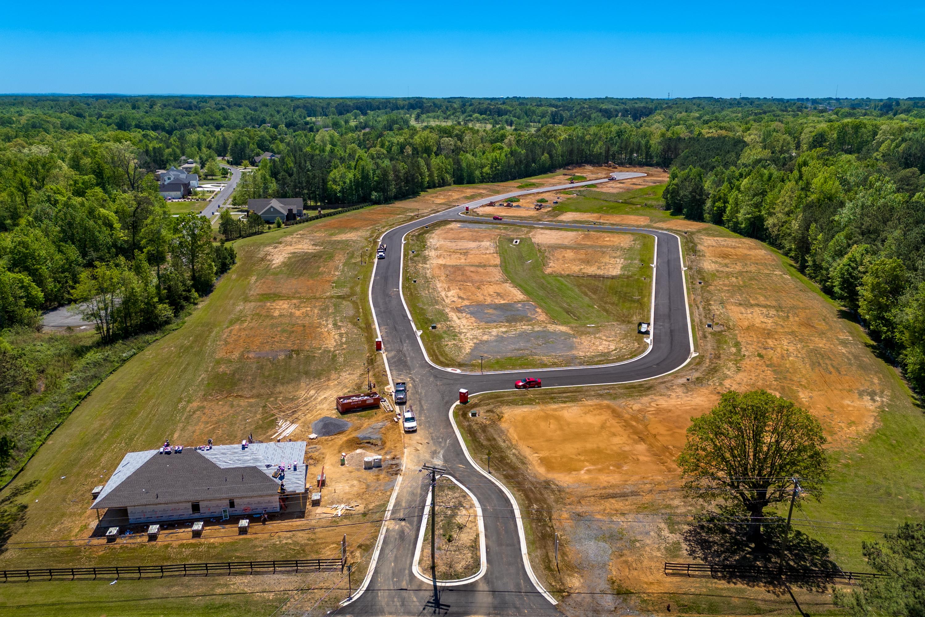 Aerial view of The Highlands neighborhood construction in Arab Alabama with dirt roads, model home, and surrounding forests by Davidson Homes