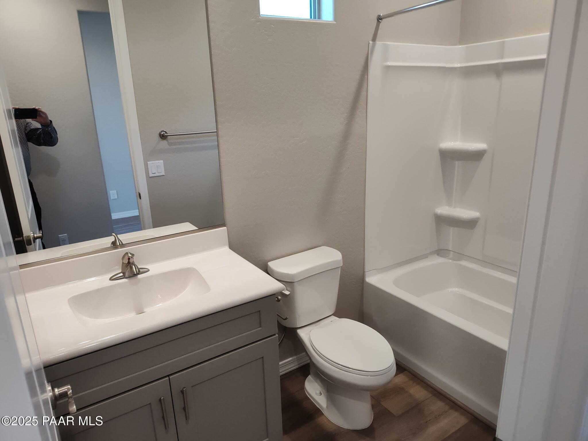 Modern bathroom featuring gray vanity sink, bathtub shower combo, and wood-look flooring in Davidson Homes The Frontier C, Prescott Valley, Arizona