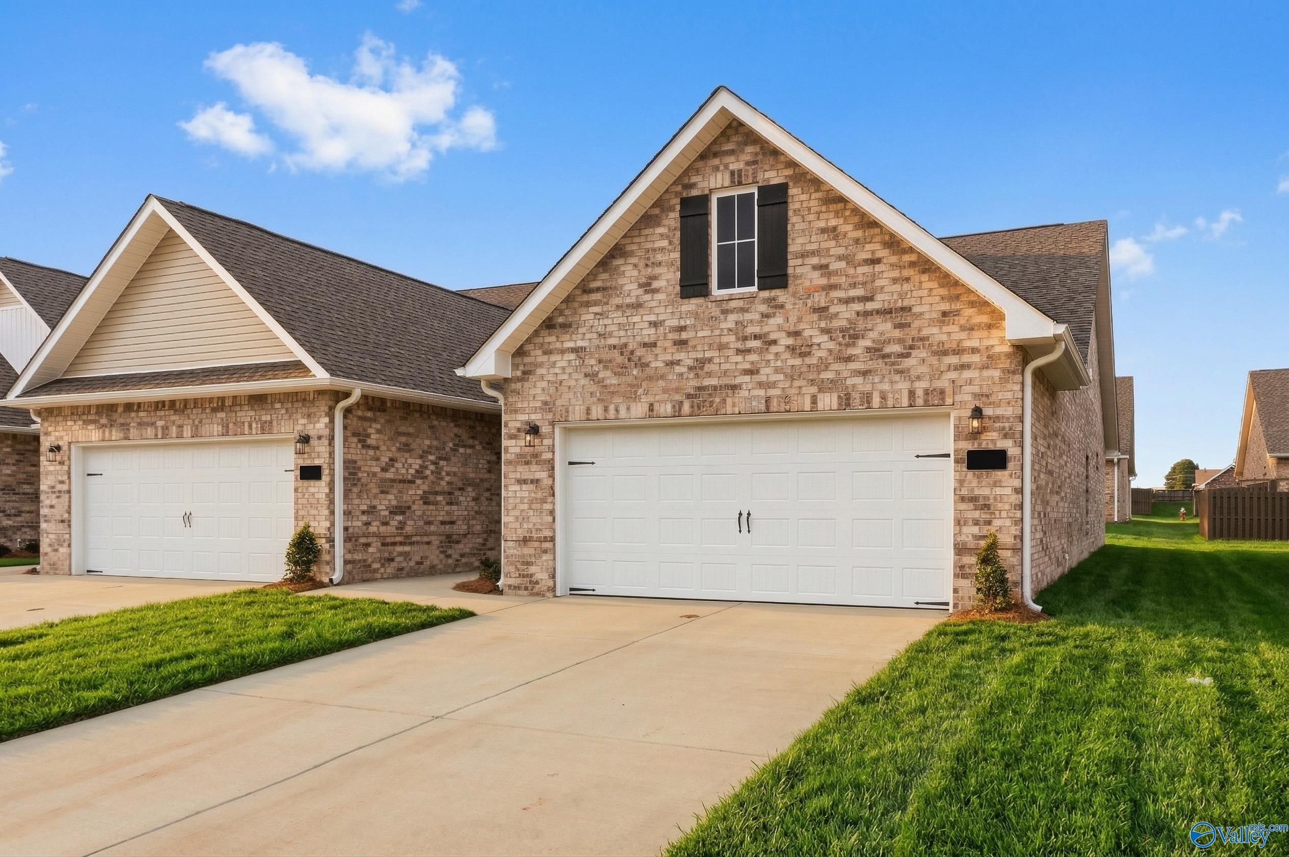 Brick 3-bedroom home with 2-car garage, driveway, and manicured lawn in The Retreat at Hollon Meadow, Decatur, Alabama