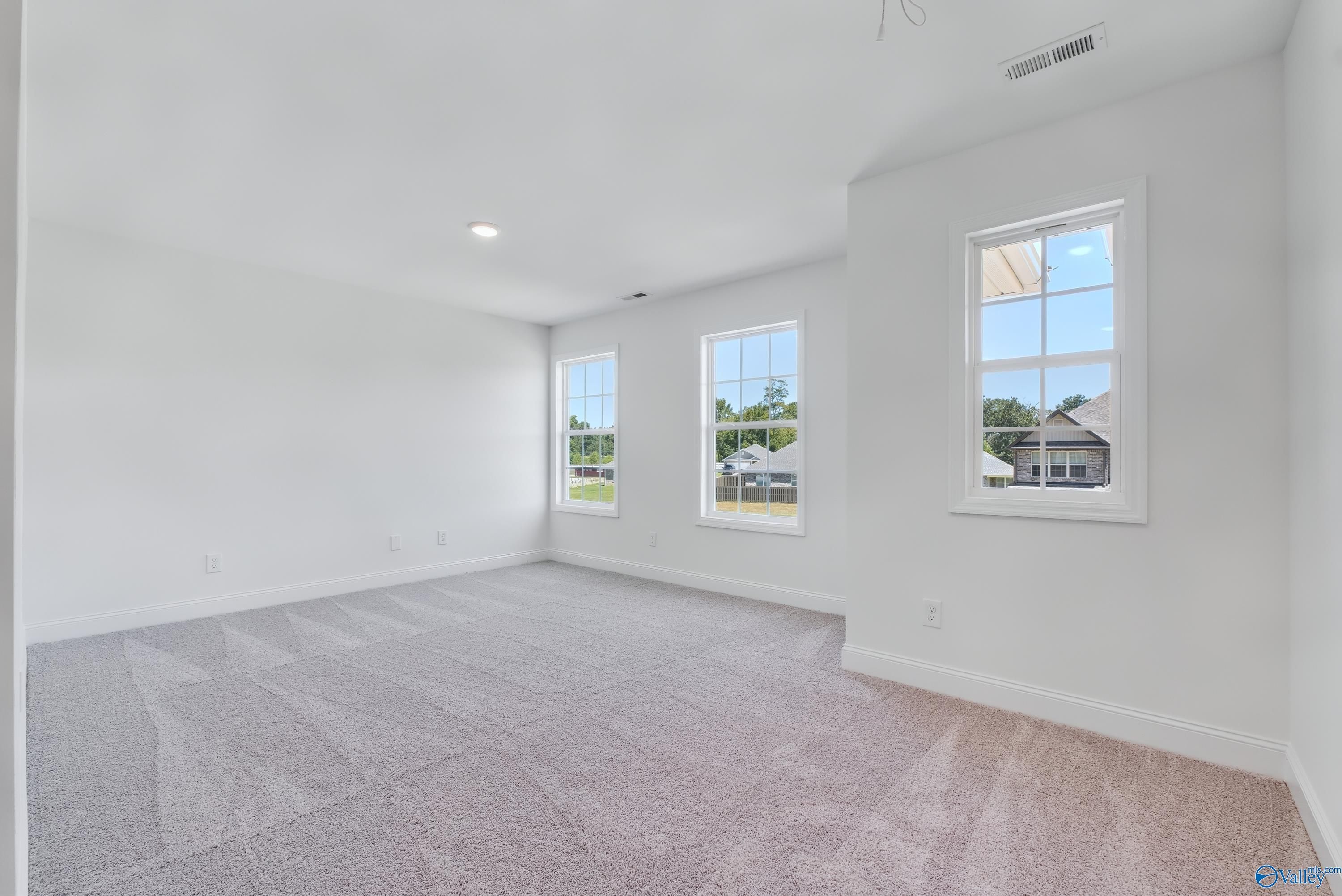 Spacious empty bedroom with large windows, white walls, beige carpet in Davidson Homes The Shelby A, Arab, Alabama