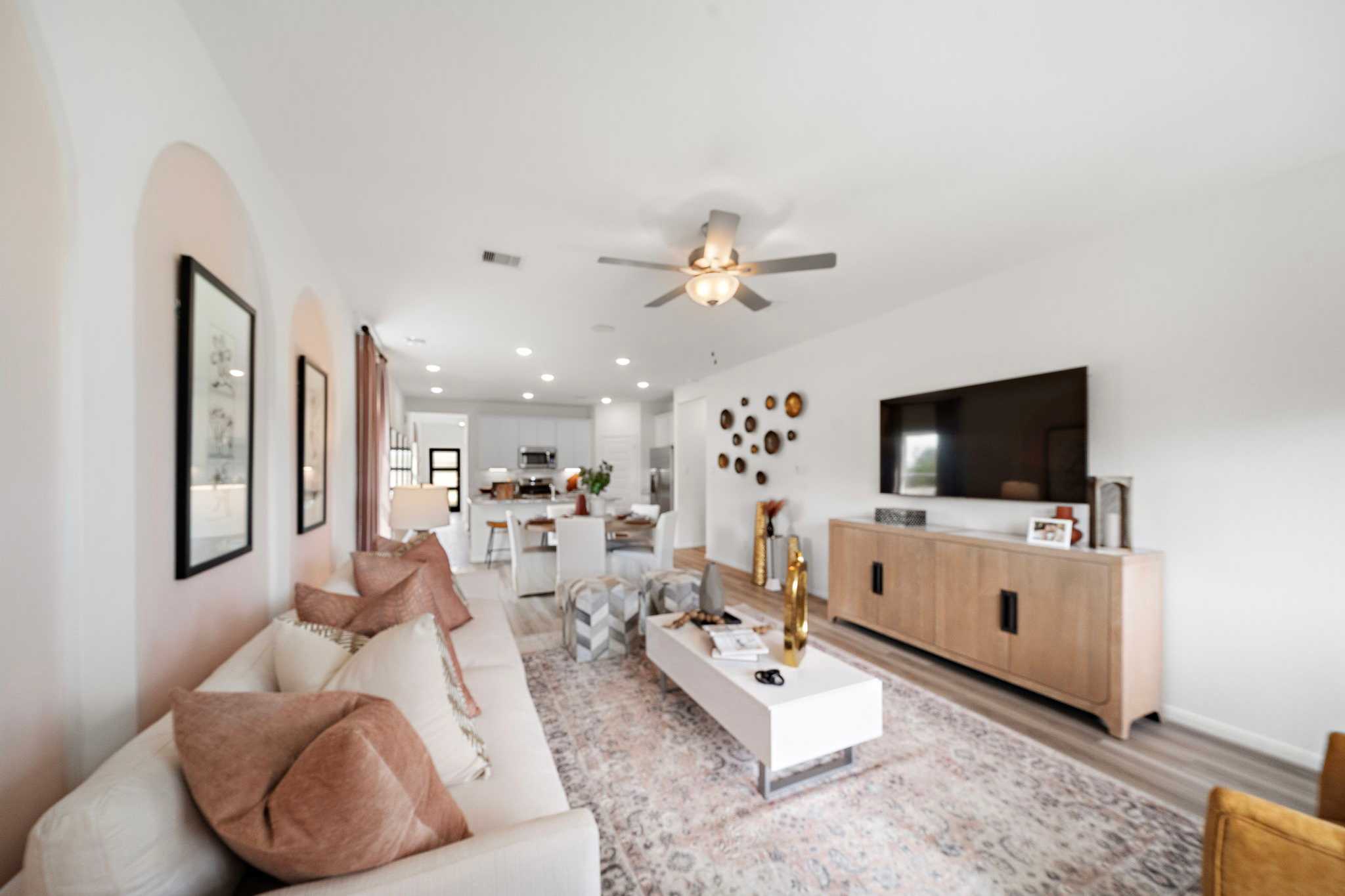 Spacious open-concept living room at The Villages at WestPointe in Dayton TX by Davidson Homes with white sofa, neutral rug, and modern kitchen