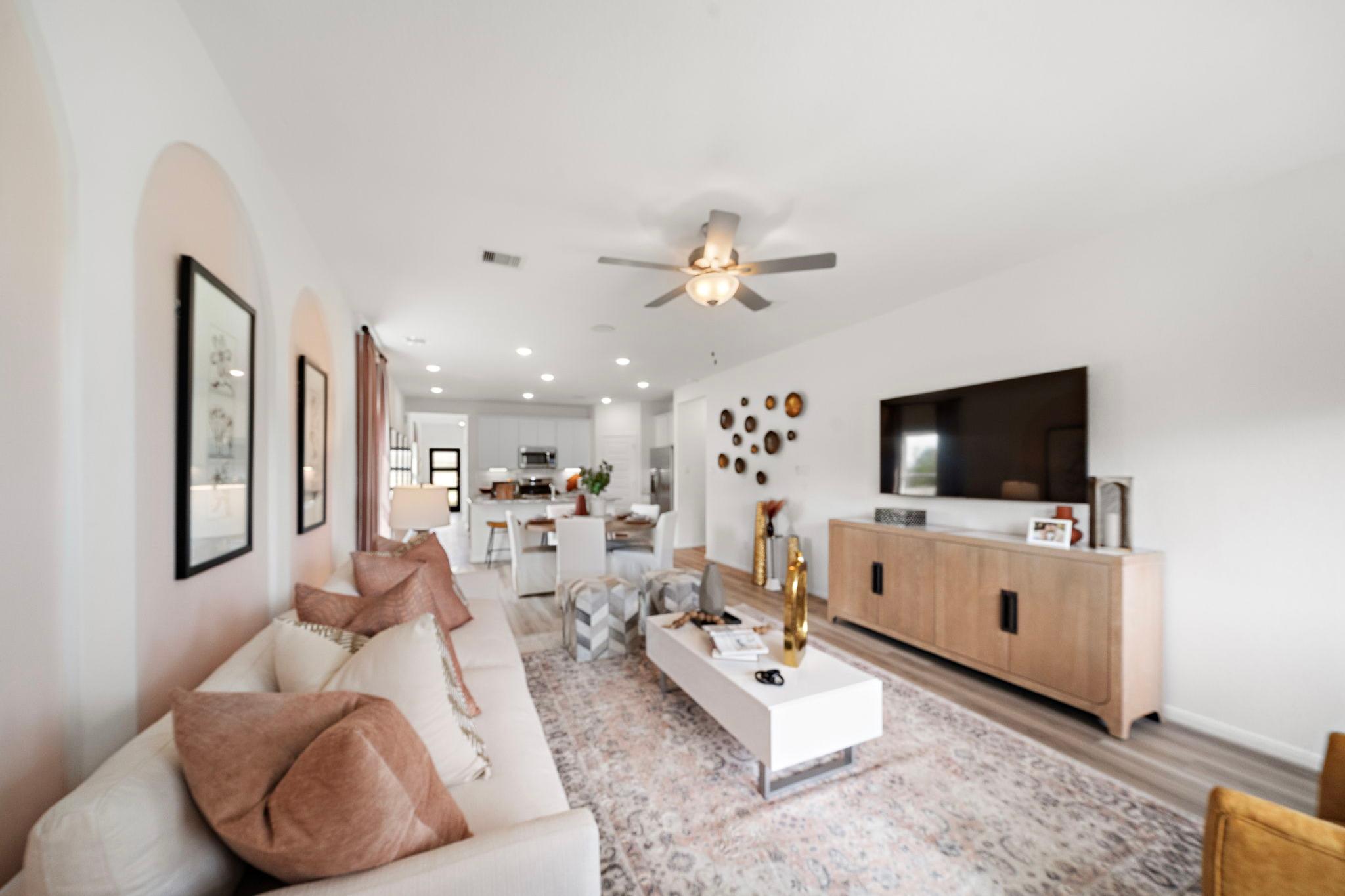 Spacious open-concept living room at The Villages at WestPointe in Dayton TX by Davidson Homes with white sofa, neutral rug, and modern kitchen