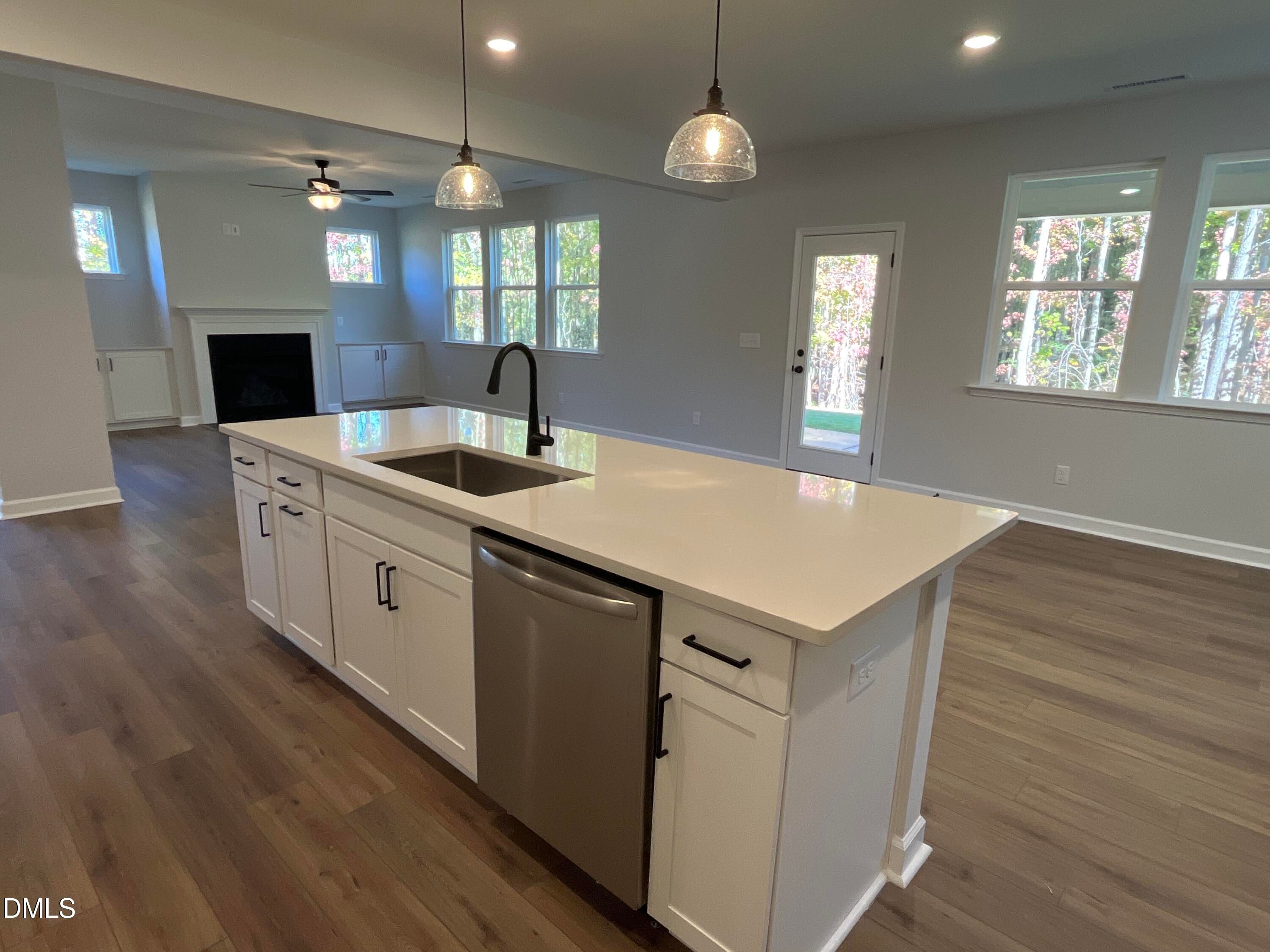 White kitchen island with quartz countertops, pendant lights, and hardwood floors in Davidson Homes The Beech C, Wake Forest, NC