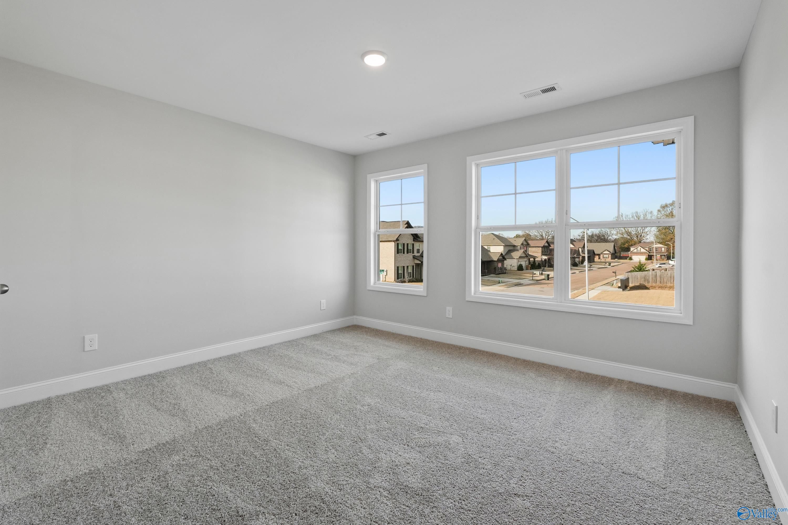 Bright secondary bedroom with large windows overlooking neighborhood, gray walls and carpet in The Camden B, Huntsville, Alabama