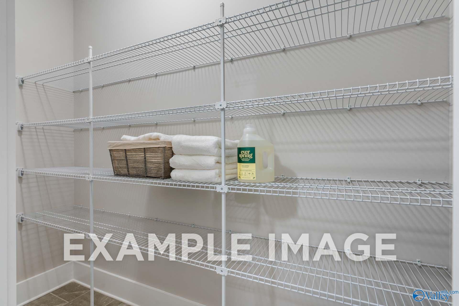 Wire shelving storage closet with folded towels and laundry detergent in Davidson Homes The Harrison floor plan, Hartselle, Alabama