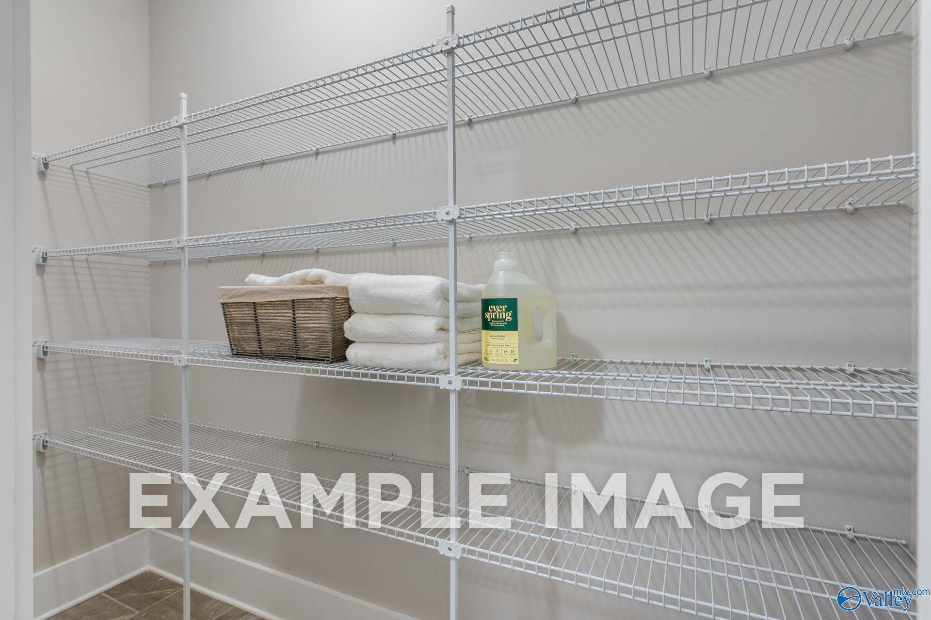 Wire shelving storage closet with folded towels and laundry detergent in Davidson Homes The Harrison floor plan, Hartselle, Alabama
