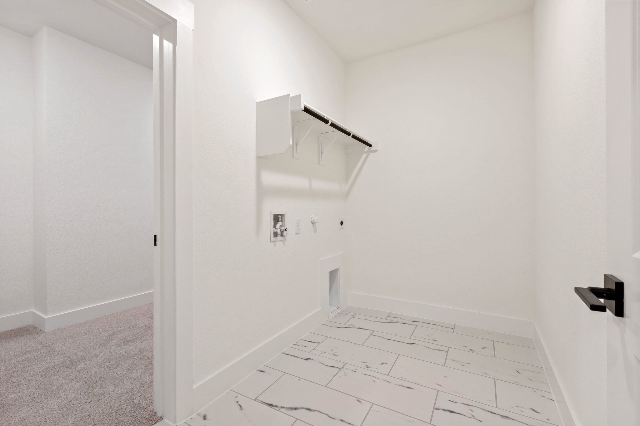 Bright laundry room with white marble-look tile flooring in The Rockford C floor plan by Davidson Homes, Josephine, TX.