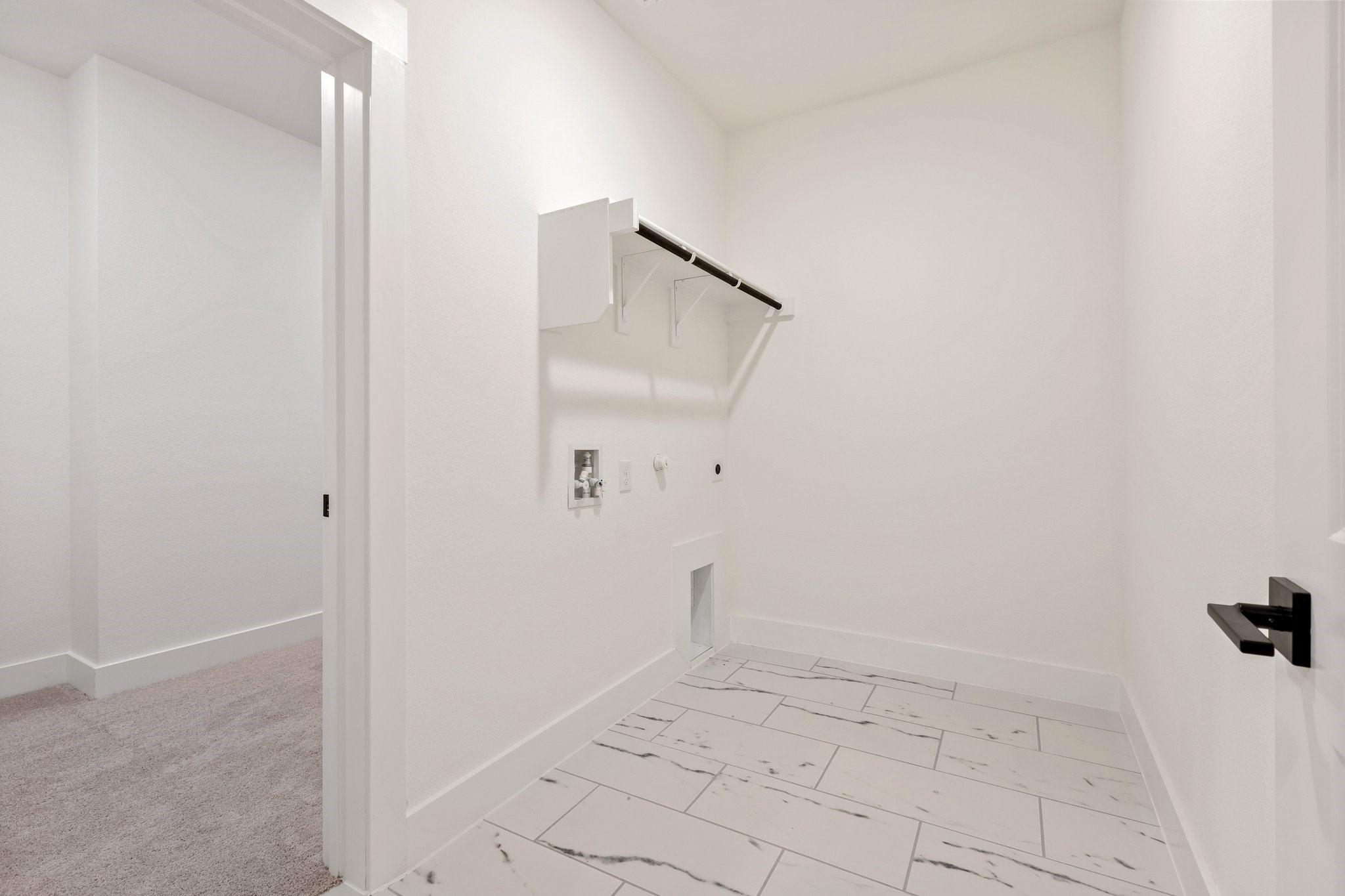 Bright laundry room with white marble-look tile flooring in The Rockford C floor plan by Davidson Homes, Josephine, TX.