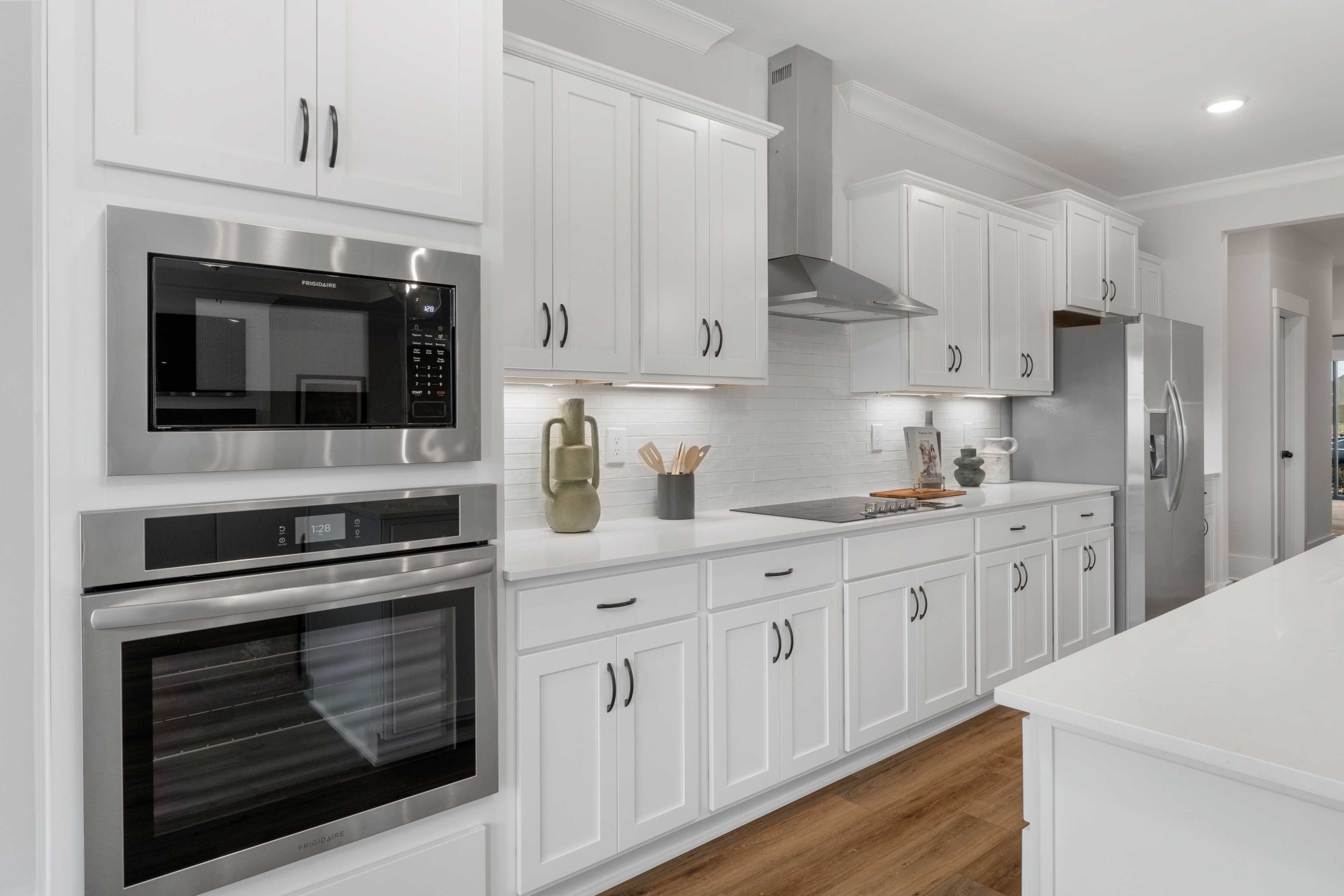 Spacious white kitchen in Briercreek by Davidson Homes, Meridianville AL, featuring stainless steel appliances, island and hardwood floors