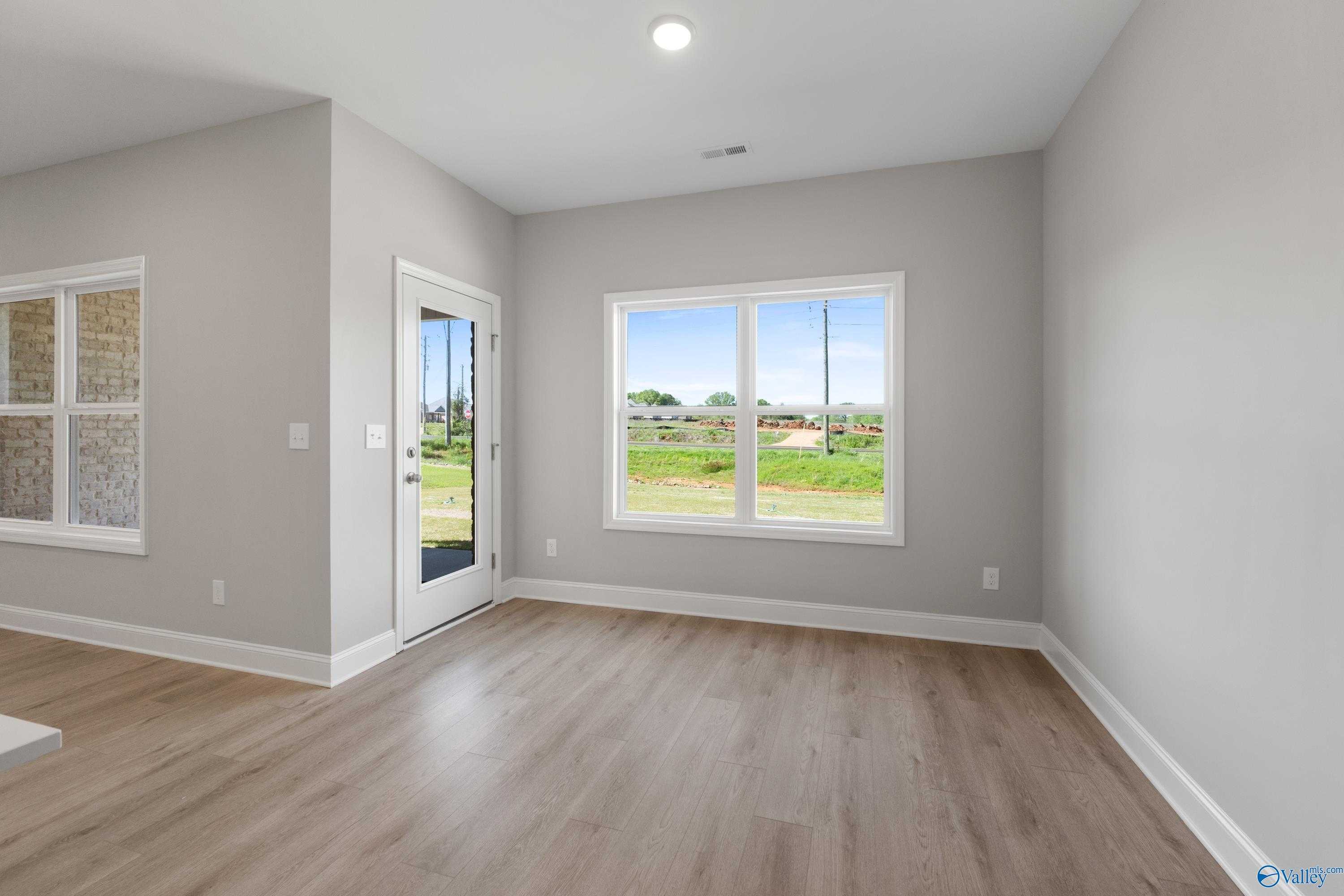 Bright room with sliding glass door and large window overlooking green fields in The Asheville C home, Athens, Alabama