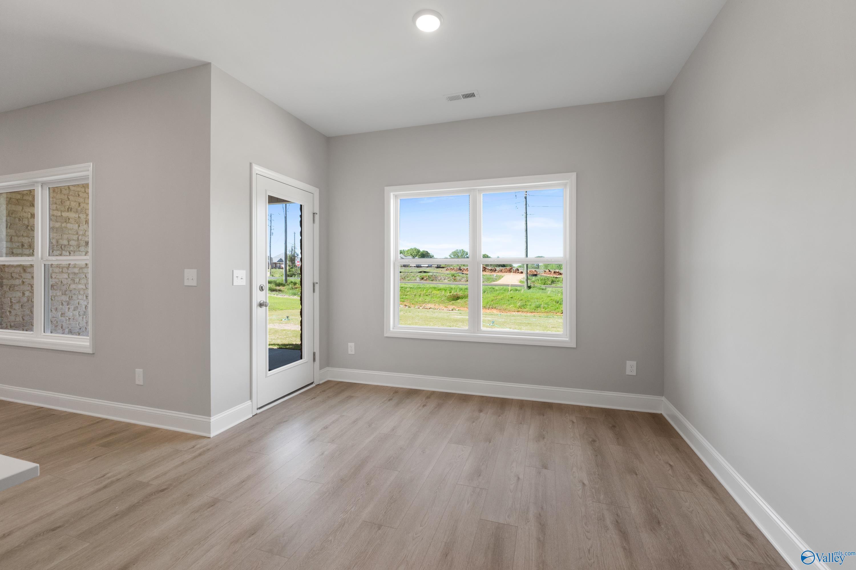 Bright room with sliding glass door and large window overlooking green fields in The Asheville C home, Athens, Alabama