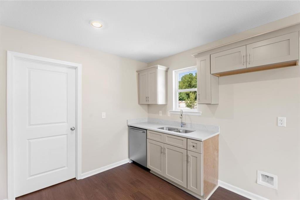 Bright kitchen with beige cabinets, stainless dishwasher, sink, and window view in The Washington 3-bedroom home, Phenix City, Alabama