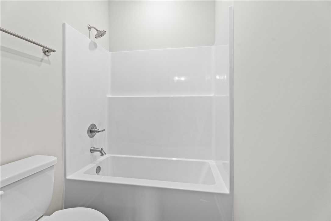 Modern white bathtub-shower combo with chrome fixtures in 3-bath 4-bedroom home, Evermore Homes The Orion, Cusseta, Alabama