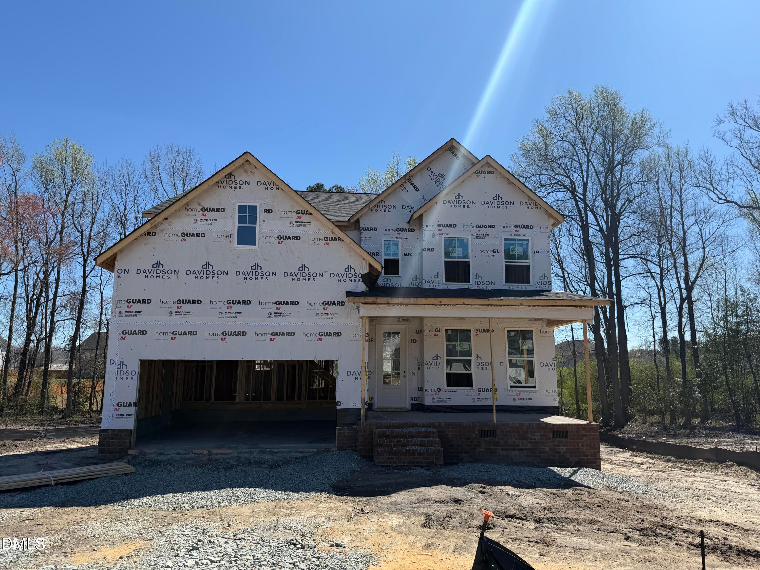 Two-story 5-bedroom home under construction with front porch, 2-car garage, and house wrap by Davidson Homes in Wellers Knoll, Lillington, NC
