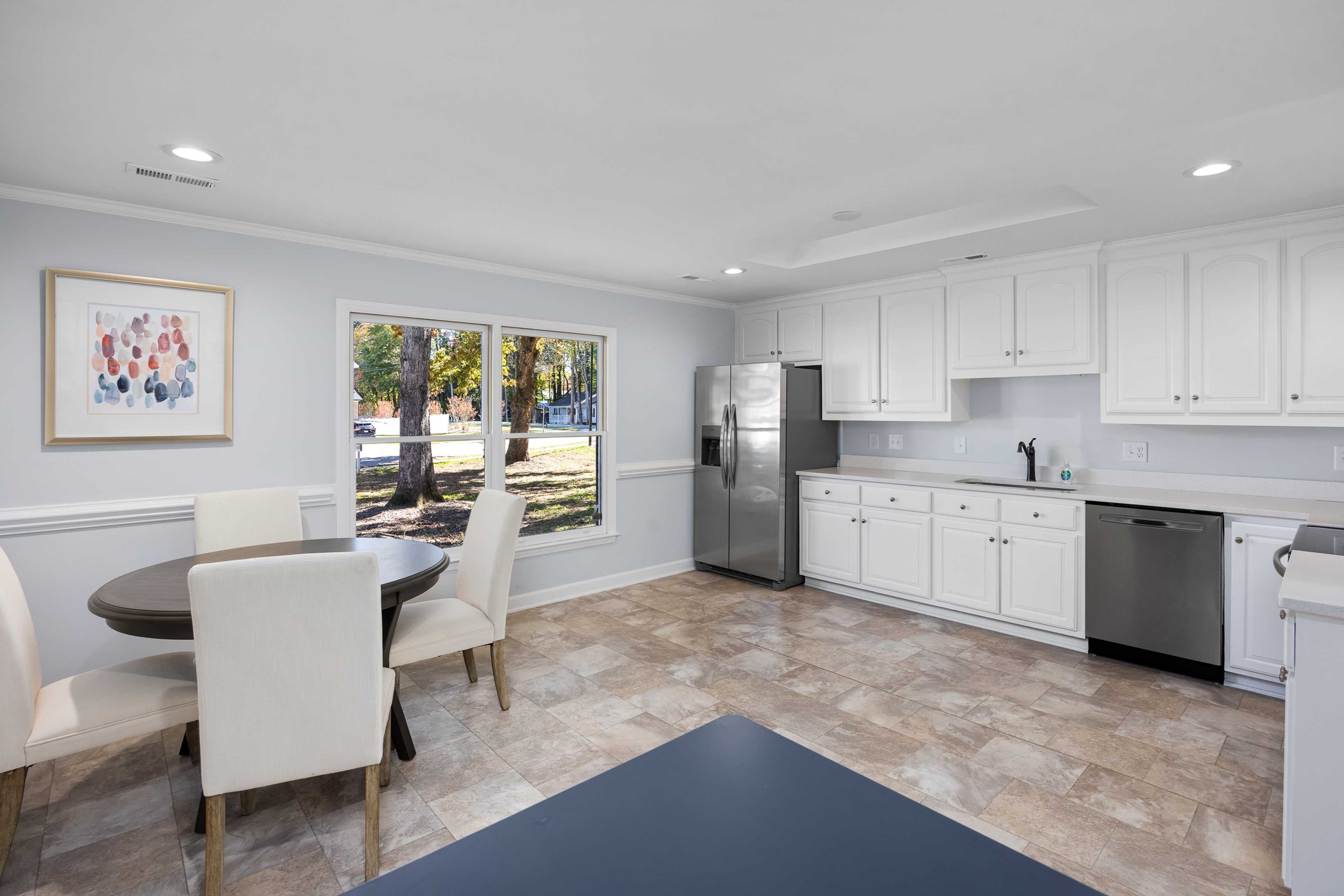 Bright kitchen dining area at Stagecoach Corner in Mebane NC with white cabinets, round table, and tree-view window