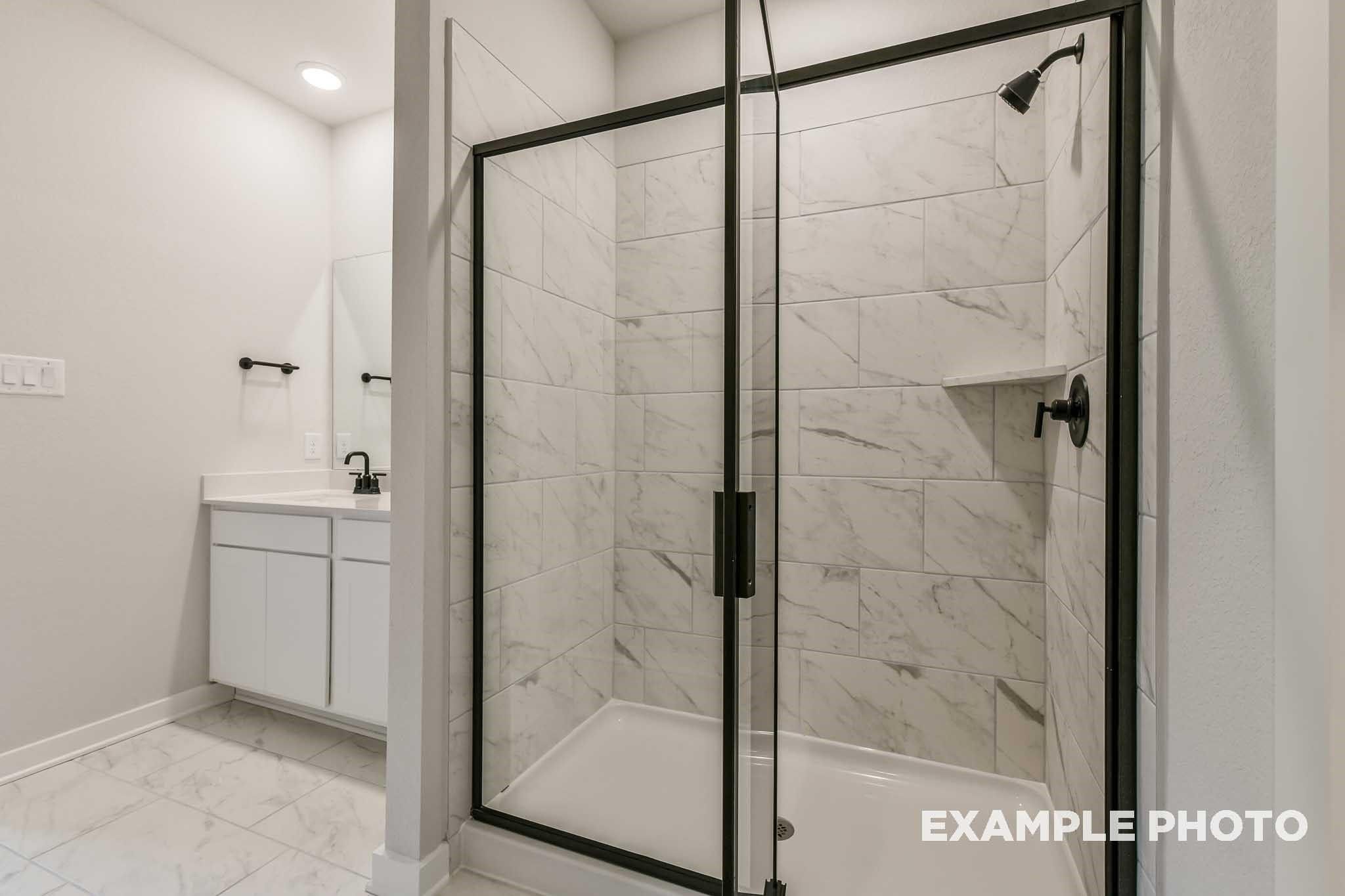 Modern master bathroom with frameless glass shower, subway tile walls, and white vanity in Davidson Homes Everett C, Crosby, Texas