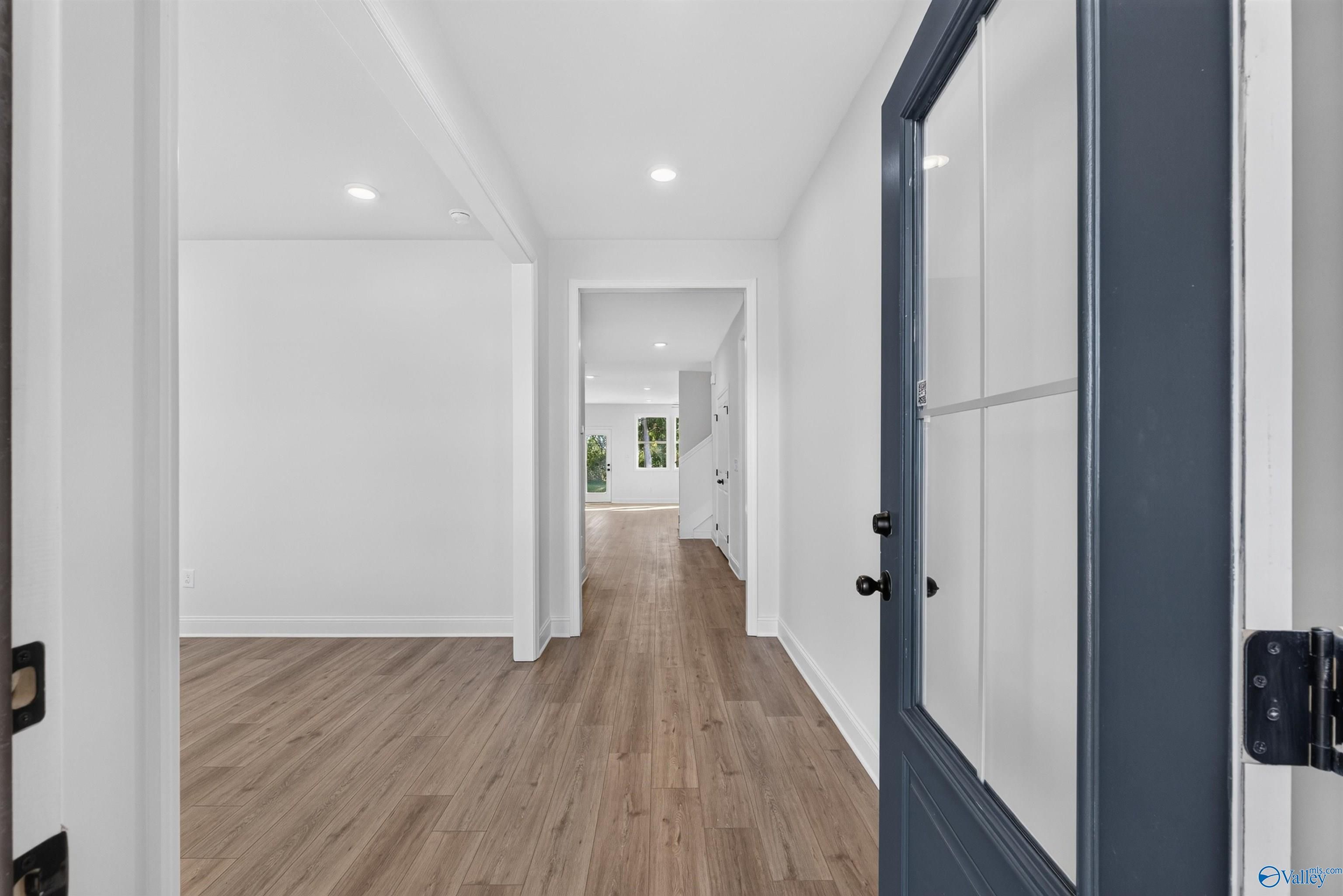 Bright entryway with navy glass-panel front door and luxury vinyl plank flooring in Davidson Homes Ashport L, New Market, AL