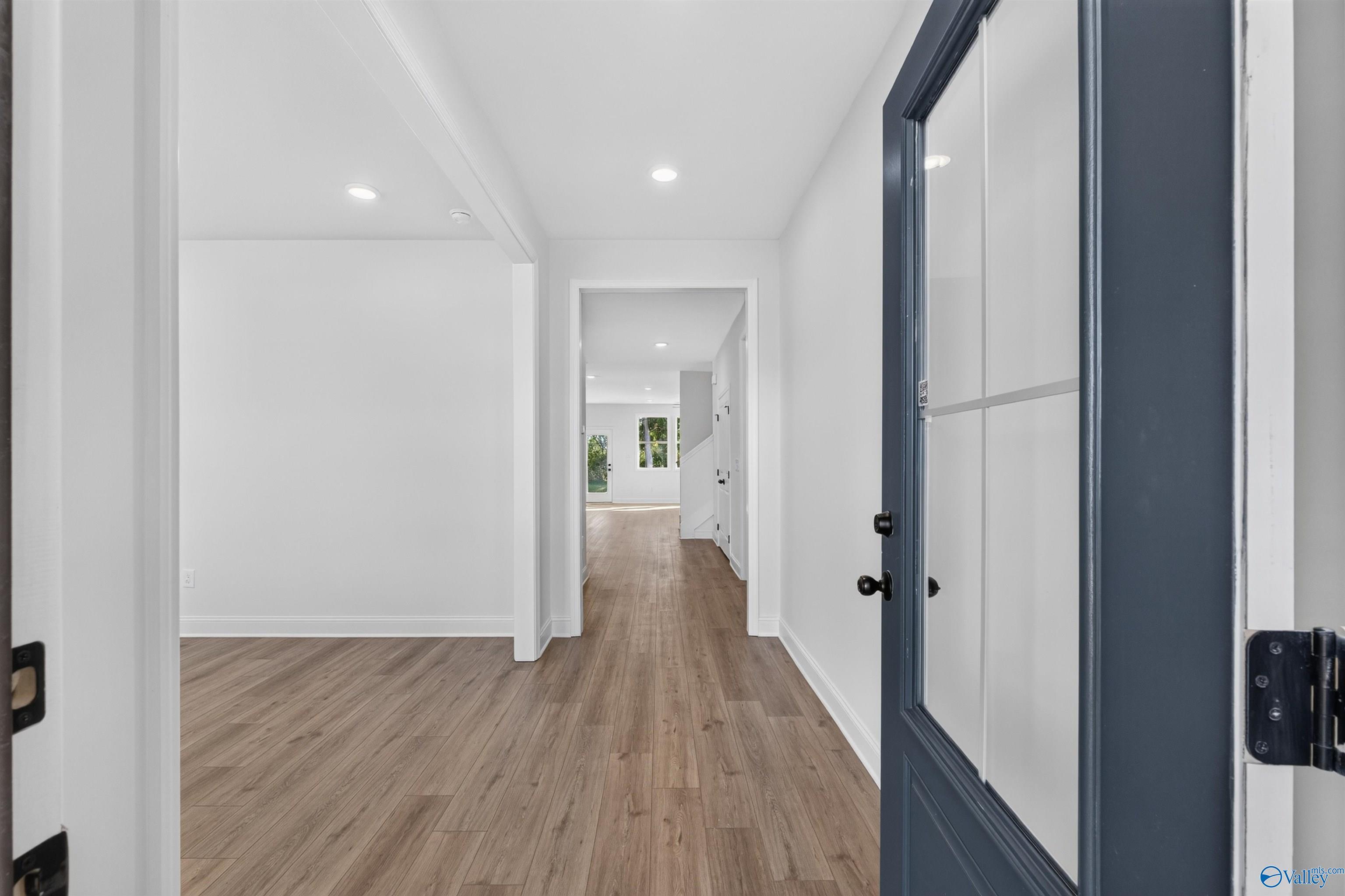 Bright entryway with navy glass-panel front door and luxury vinyl plank flooring in Davidson Homes Ashport L, New Market, AL